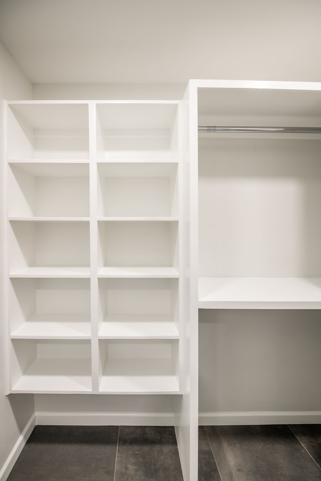An empty walk in closet with white shelves and a desk.