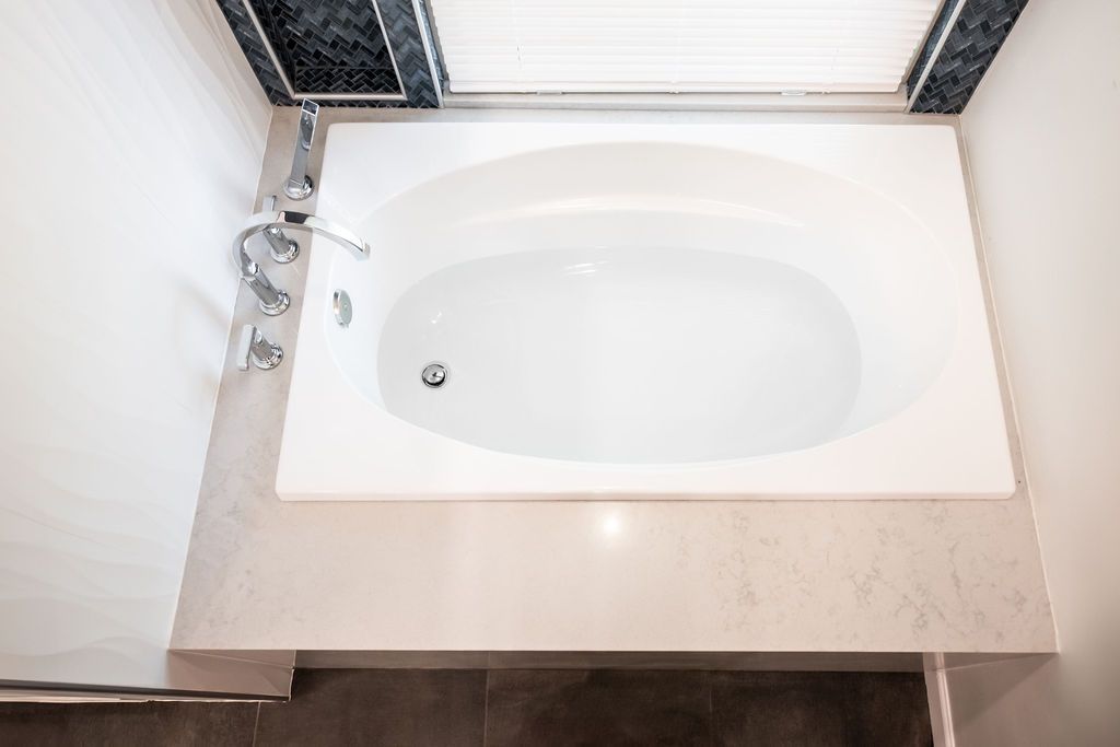 A bathtub is sitting on a counter in a bathroom next to a window.