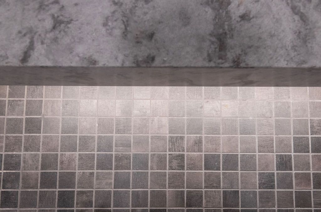 A close up of a tiled floor with a concrete wall in the background.