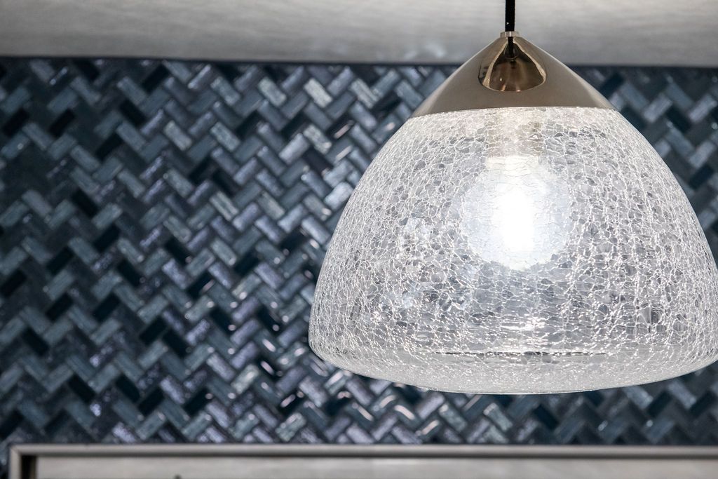 A pendant light is hanging from the ceiling in front of a blue tile wall.