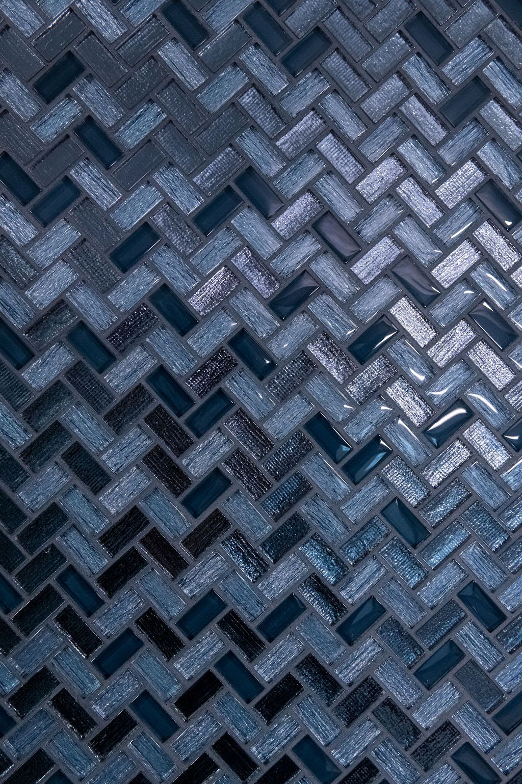A close up of a mosaic tile wall with a herringbone pattern.