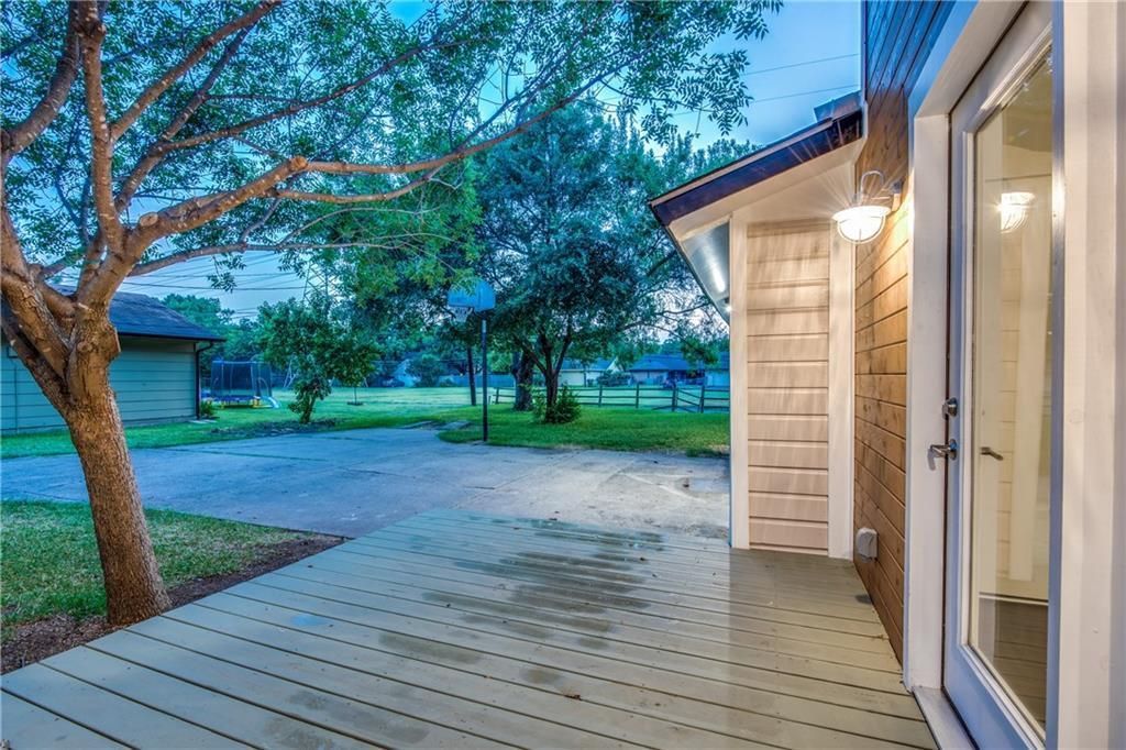 A patio with a sliding glass door and a tree in the background.