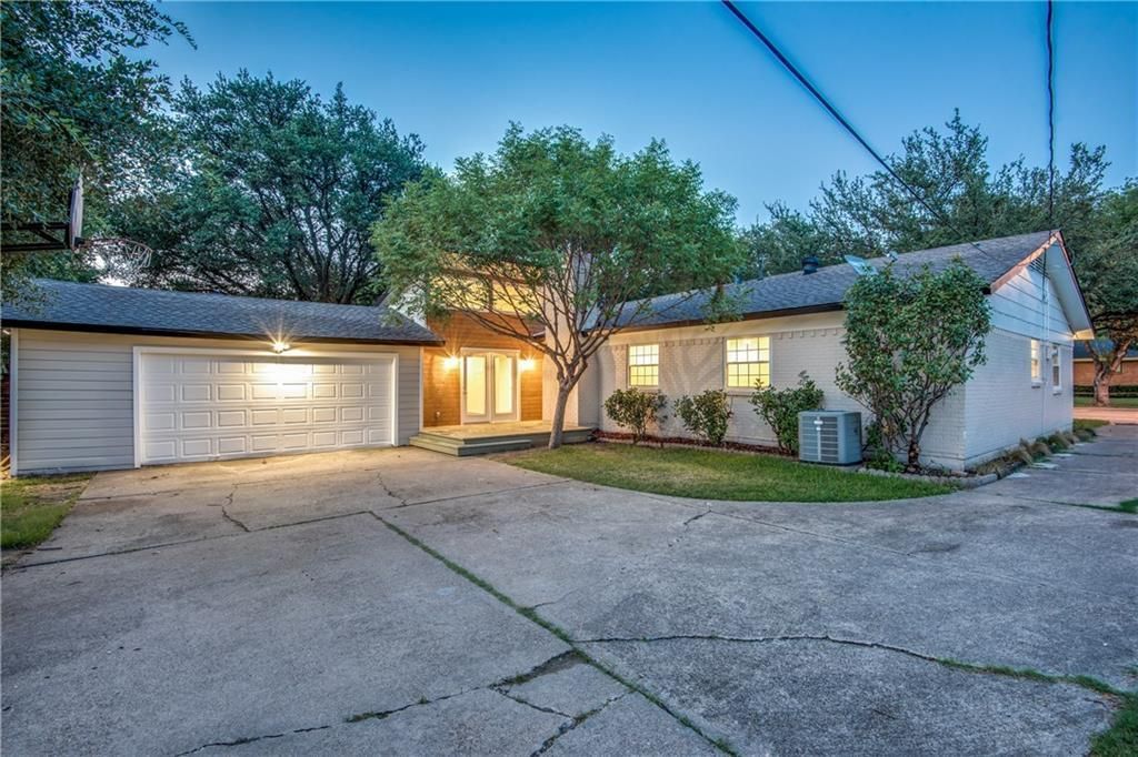 A white house with two garages and a driveway is for sale.