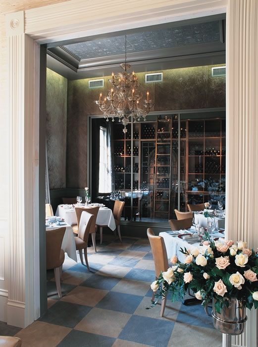 A dining room with tables and chairs and a vase of flowers