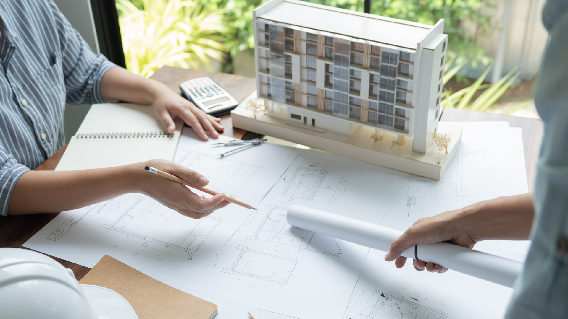 A group of people are sitting at a table with a model of a building.