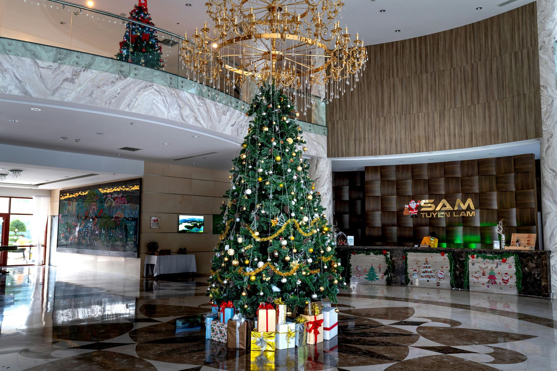 There is a christmas tree in the middle of the lobby of a hotel.
