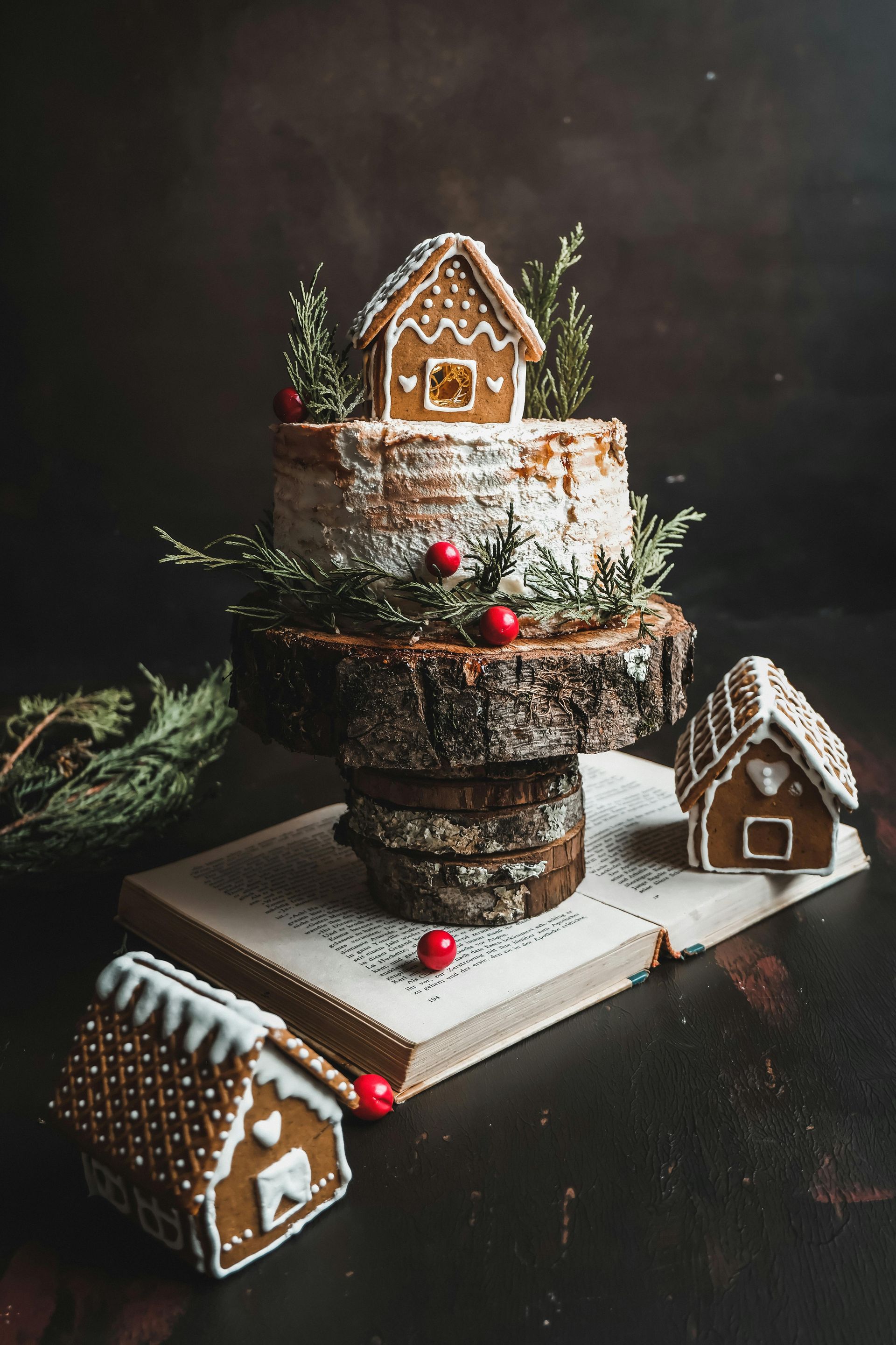 A gingerbread house cake is sitting on top of a wooden stump.