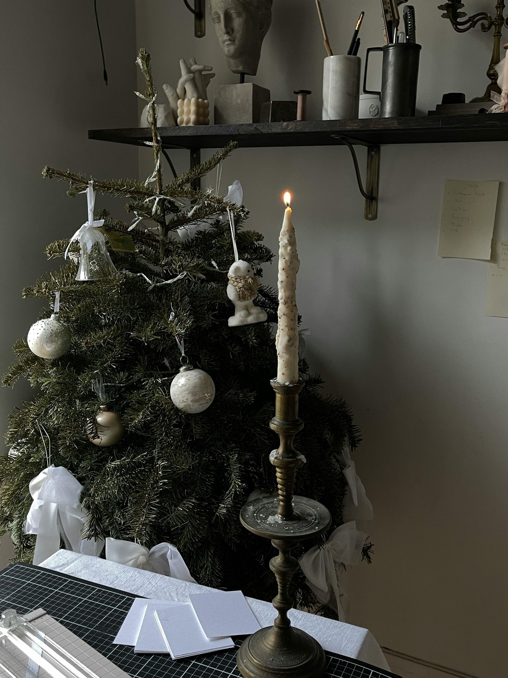 A candle is lit in front of a christmas tree