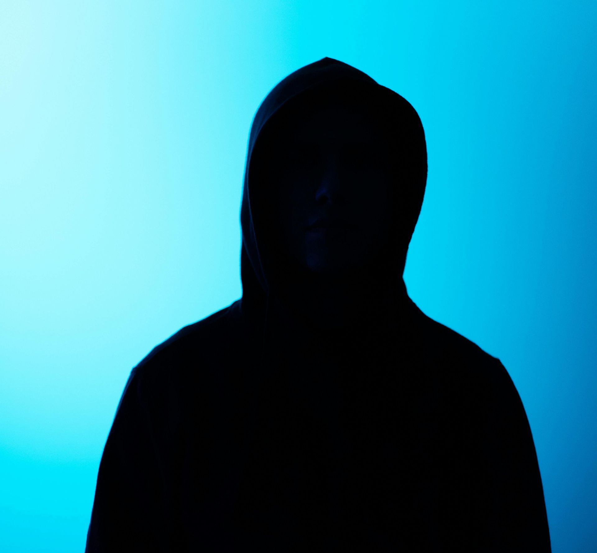A silhouette of a man in a hooded sweatshirt against a blue background.