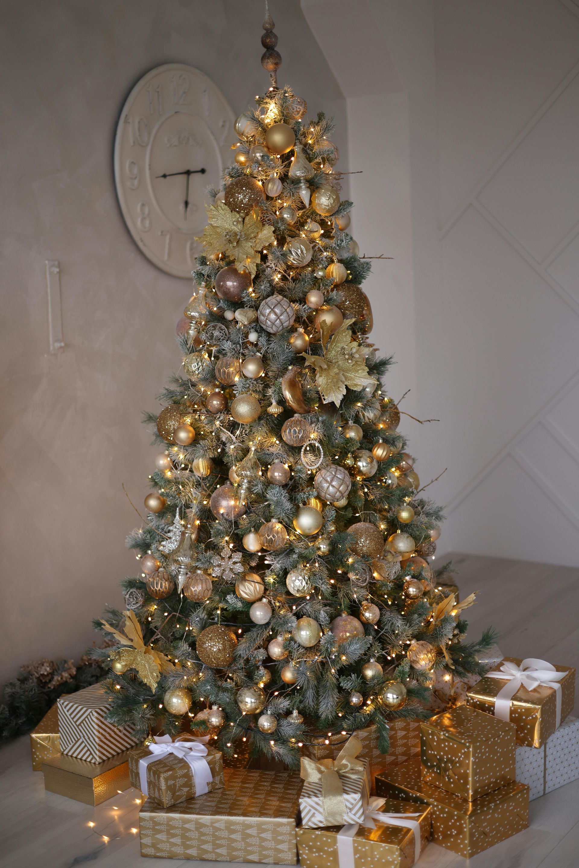 A christmas tree decorated in gold and silver with gifts underneath it.