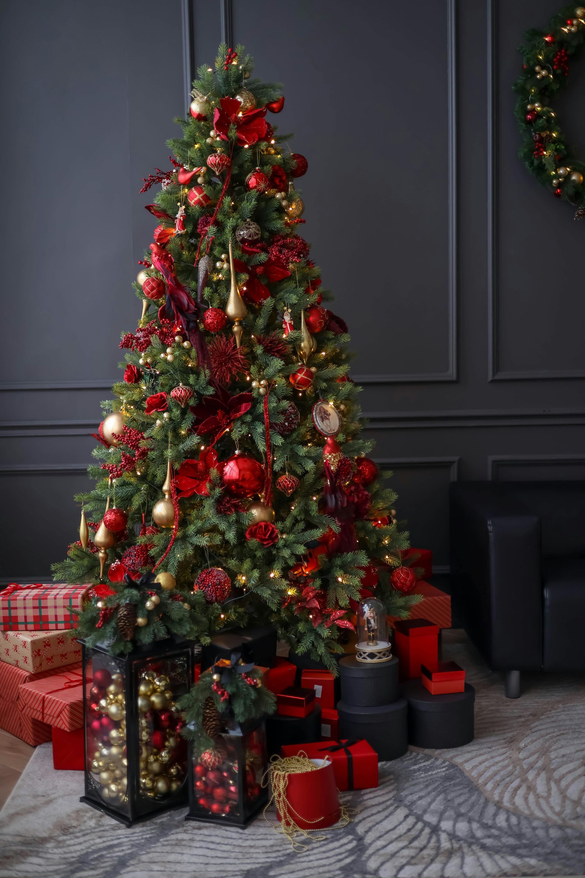 A christmas tree decorated in red and gold with gifts underneath it.