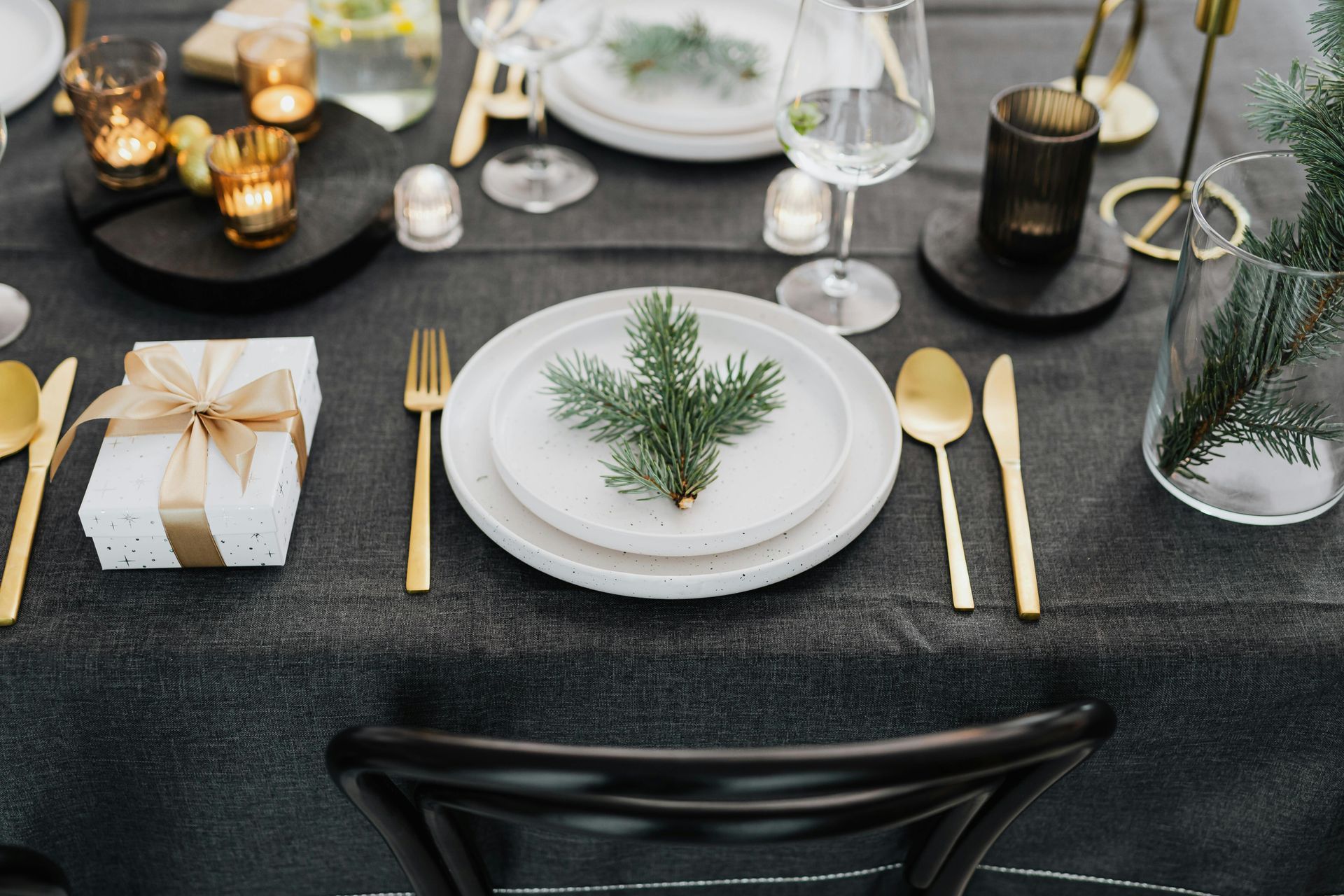 A table set for a christmas dinner with plates , silverware , and candles.