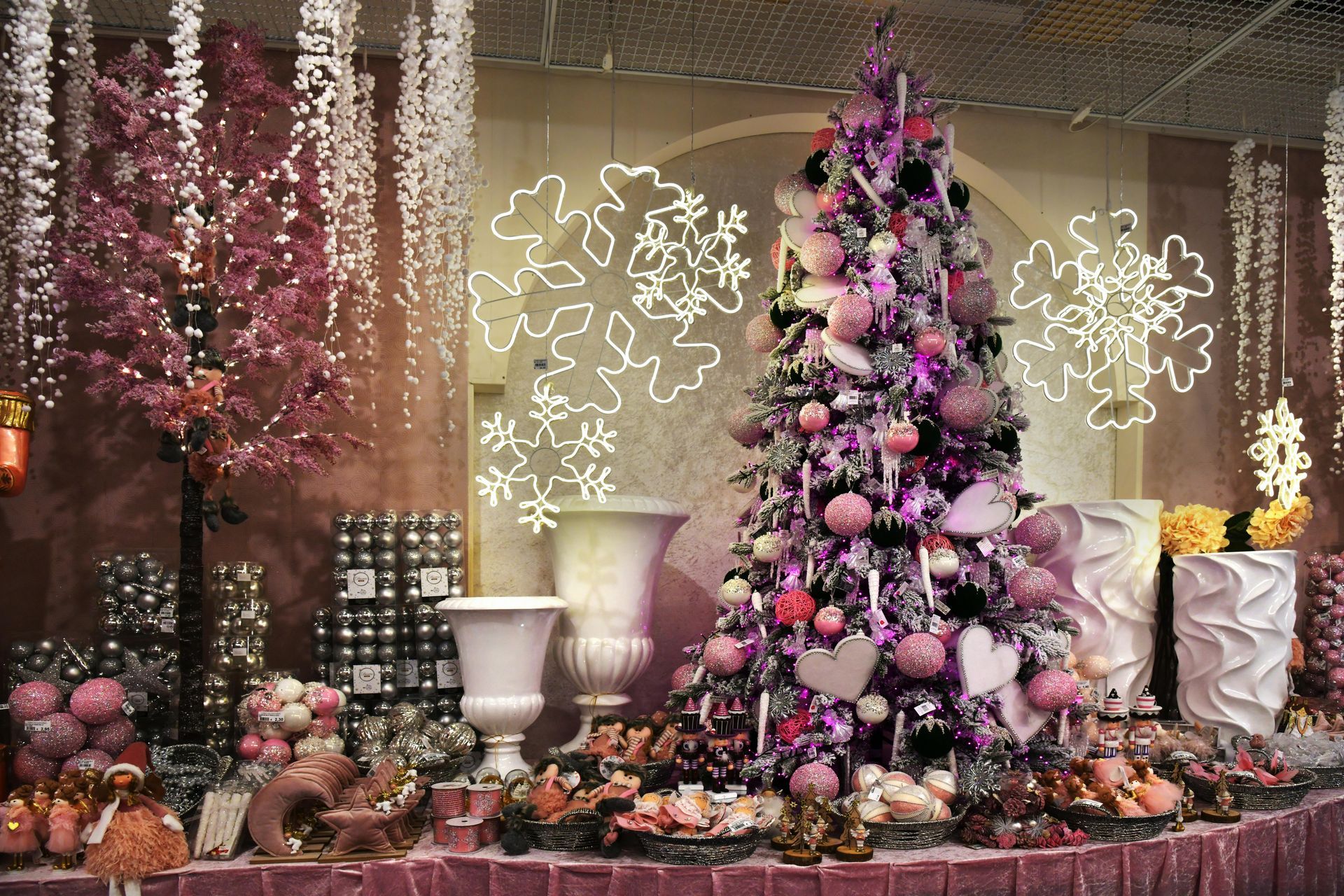 A pink christmas tree is surrounded by pink decorations