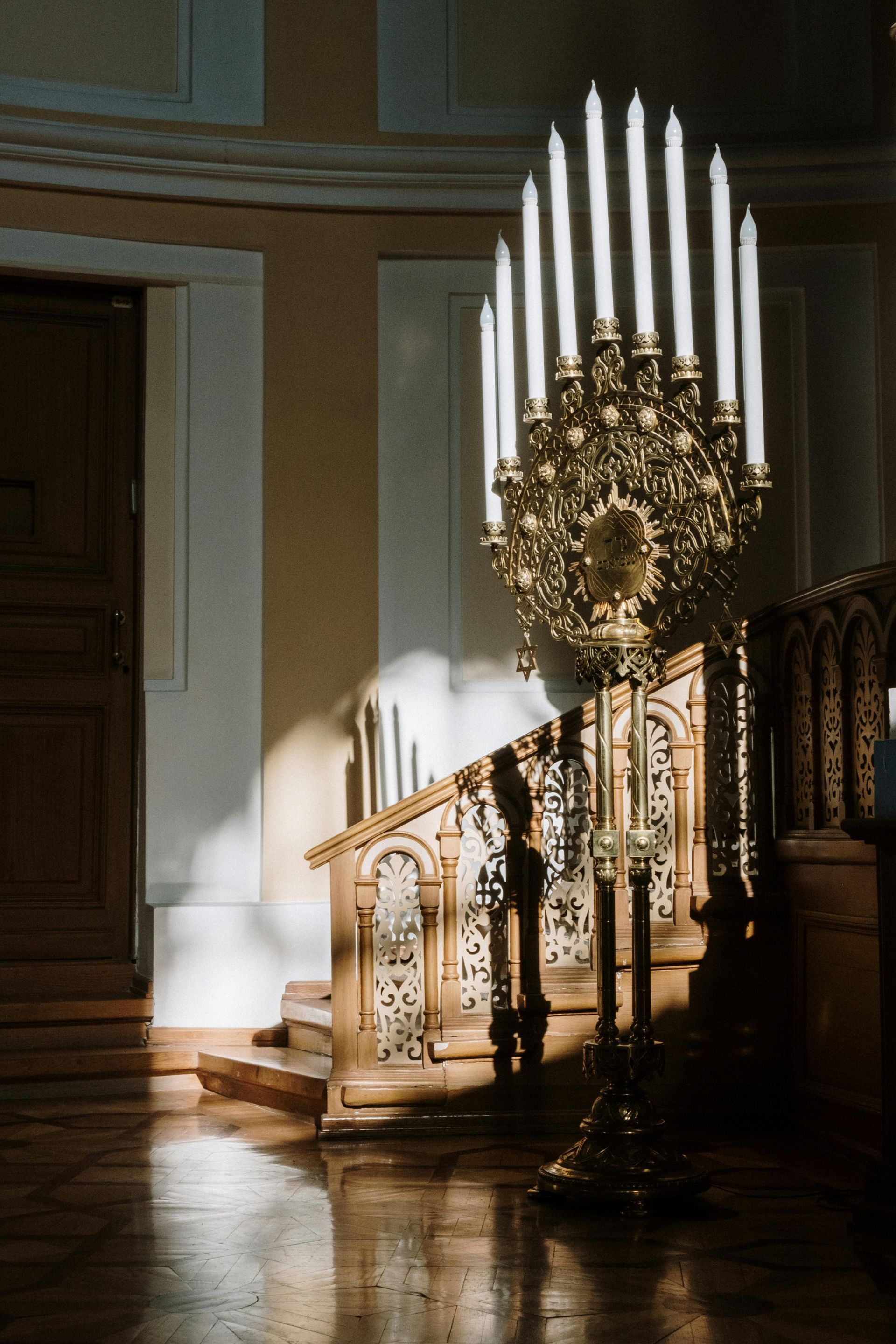 A large candle holder is sitting in front of a wooden staircase.