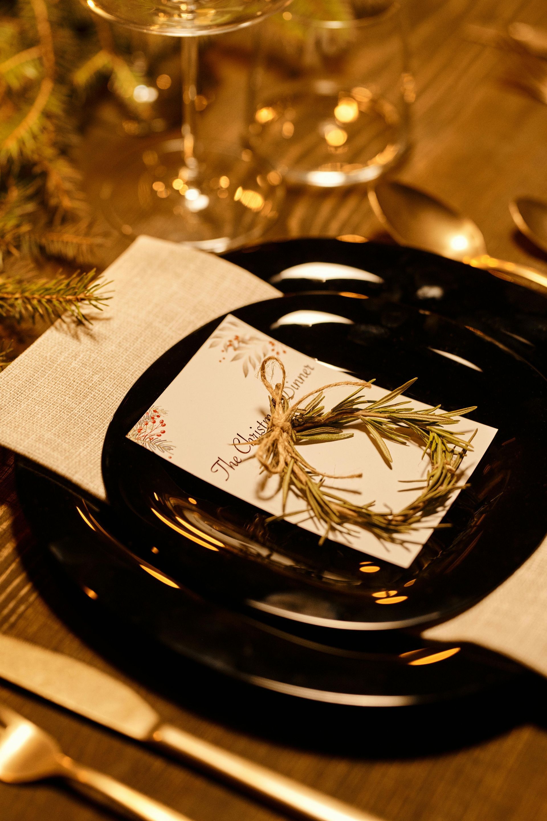 A place setting with plates , utensils , a napkin and a card with a wreath on it.