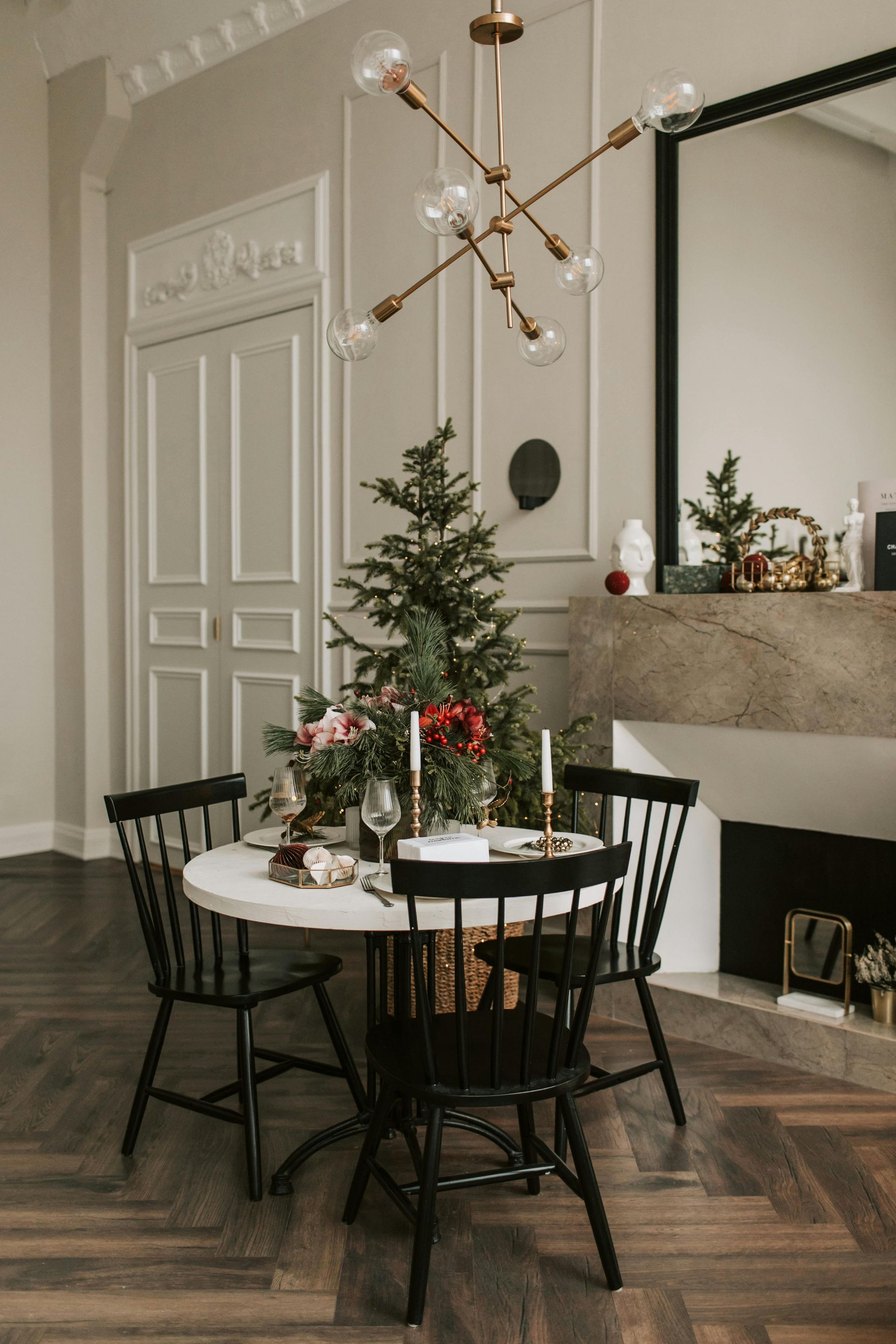 A dining room with a table and chairs and a christmas tree in the background.