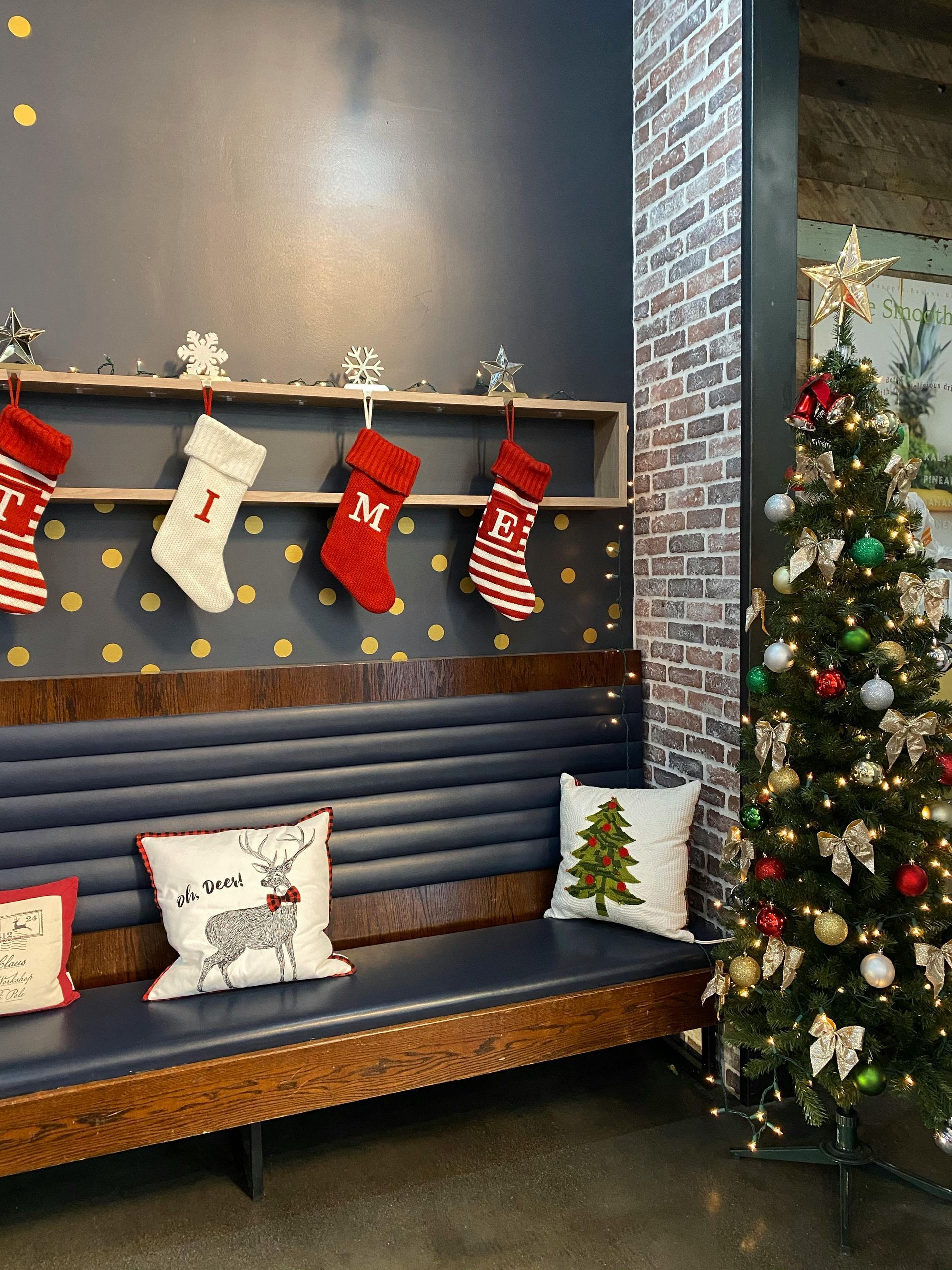 A christmas tree is sitting next to a bench with stockings hanging on the wall