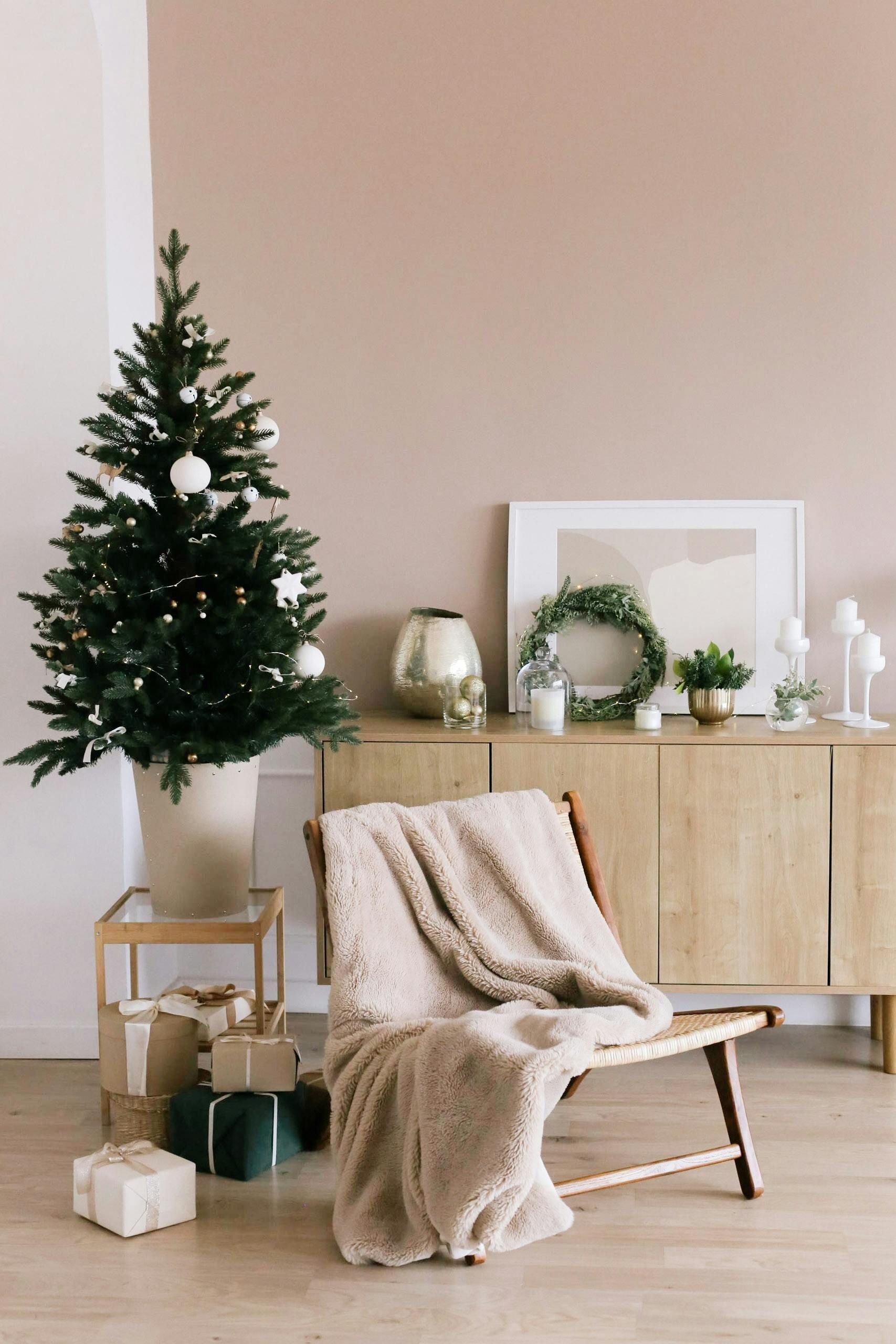 A living room decorated for christmas with a christmas tree and a chair.