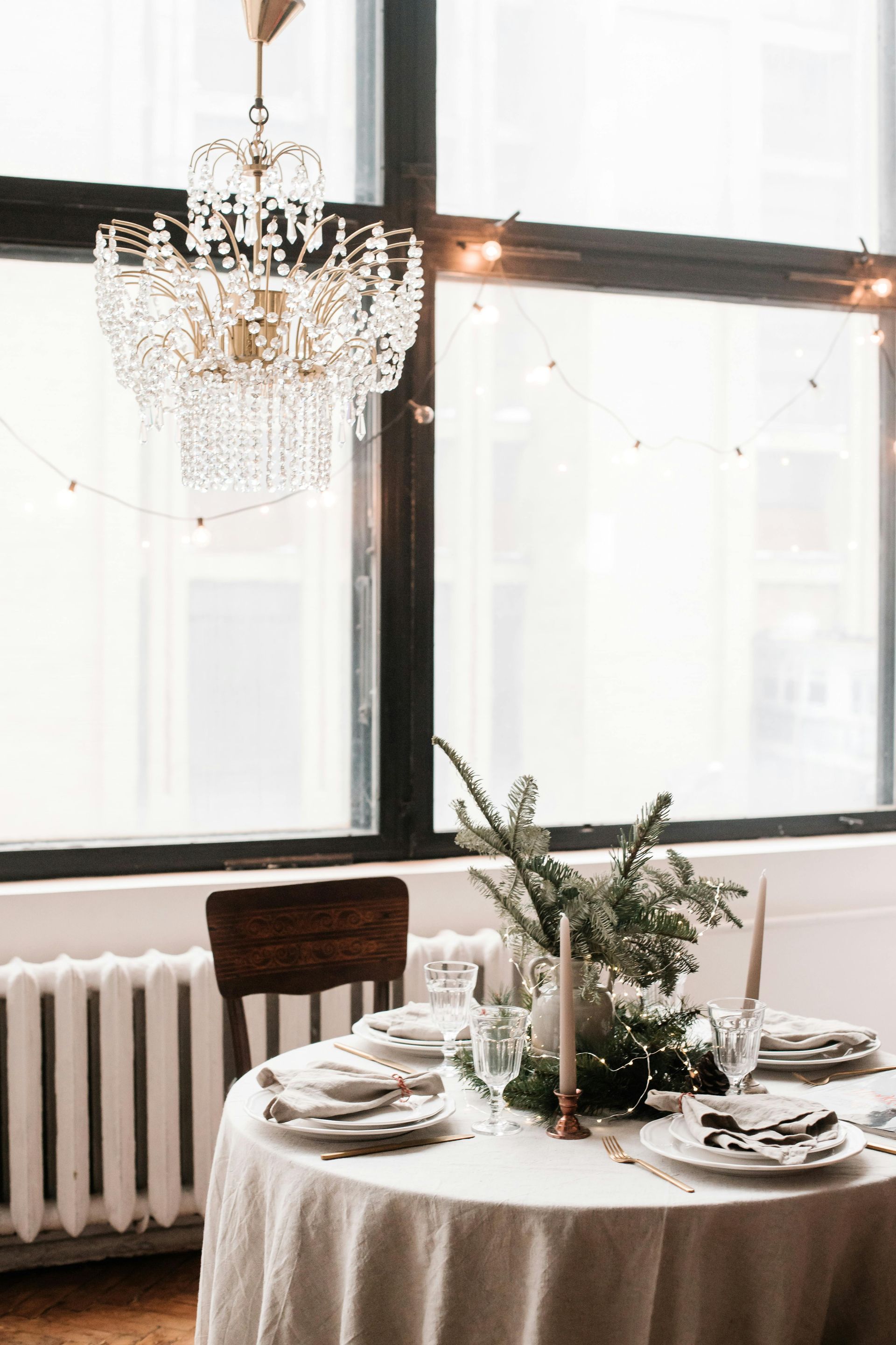 A table with plates , candles , and a chandelier hanging from the ceiling.