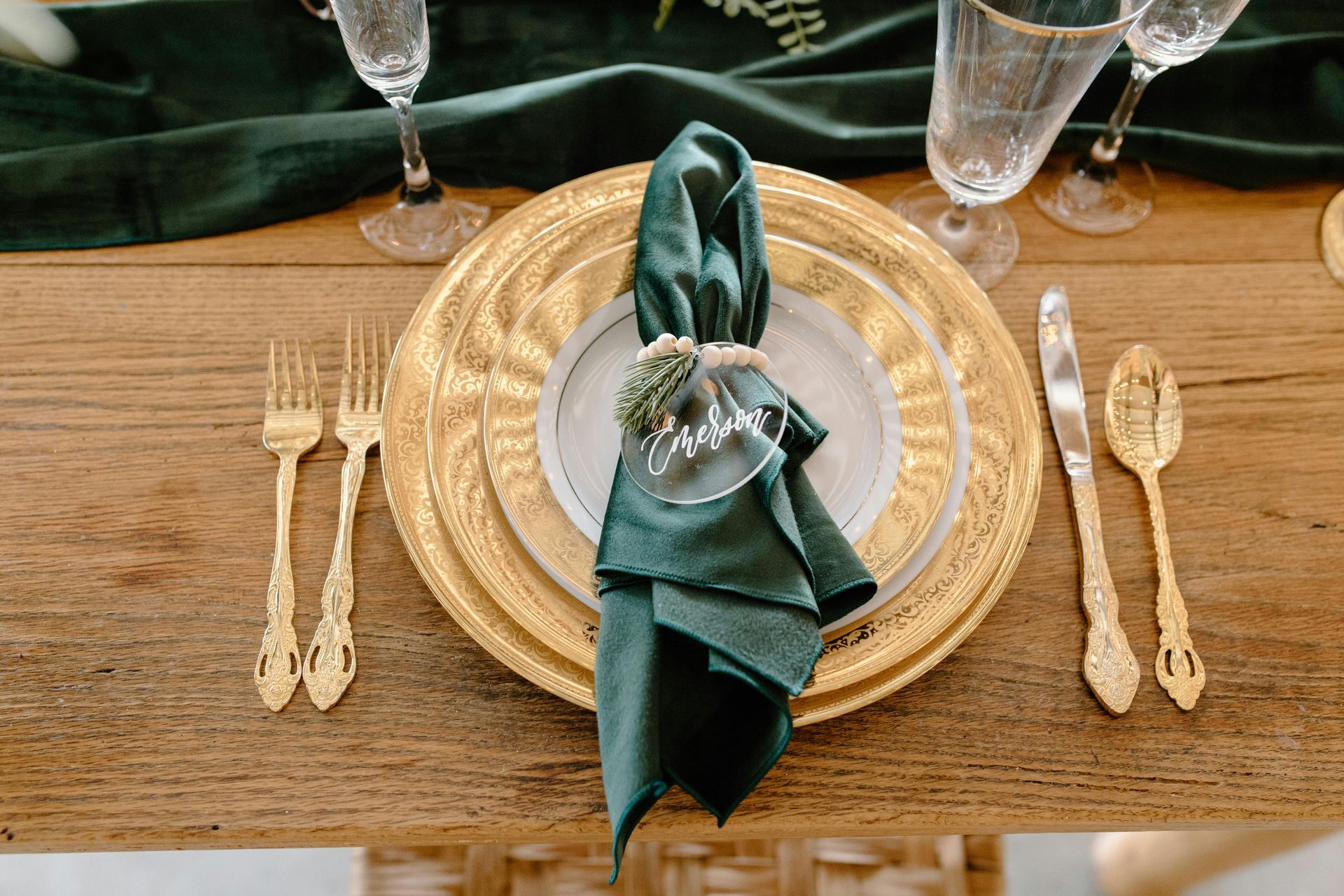 A wooden table topped with plates , silverware , and a green napkin.