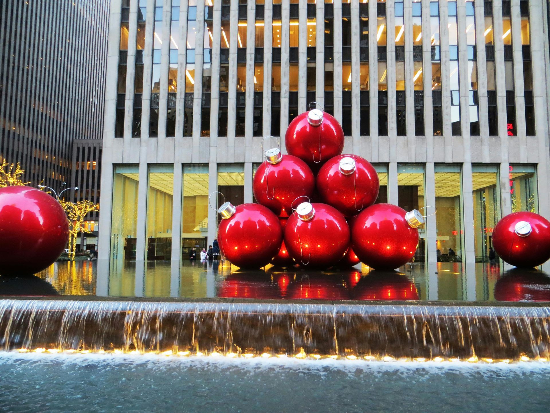 A pile of red christmas ornaments sits in front of a building
