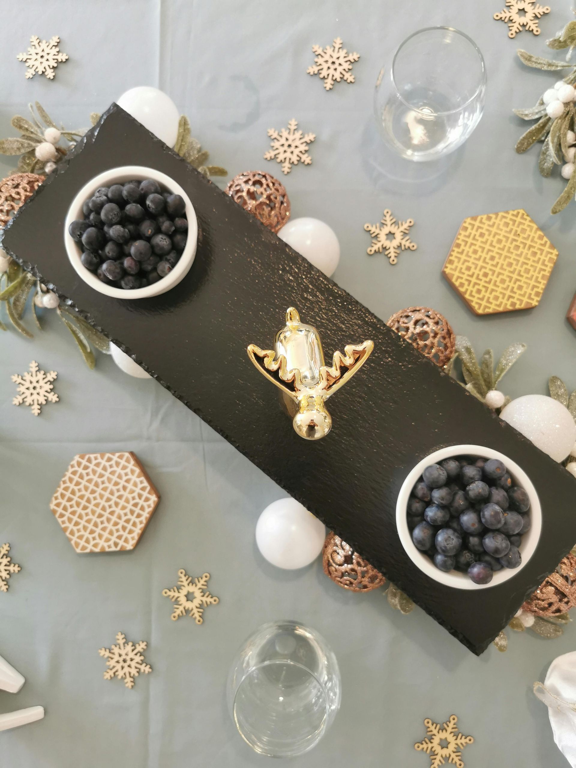 A black tray with three bowls of blueberries on it