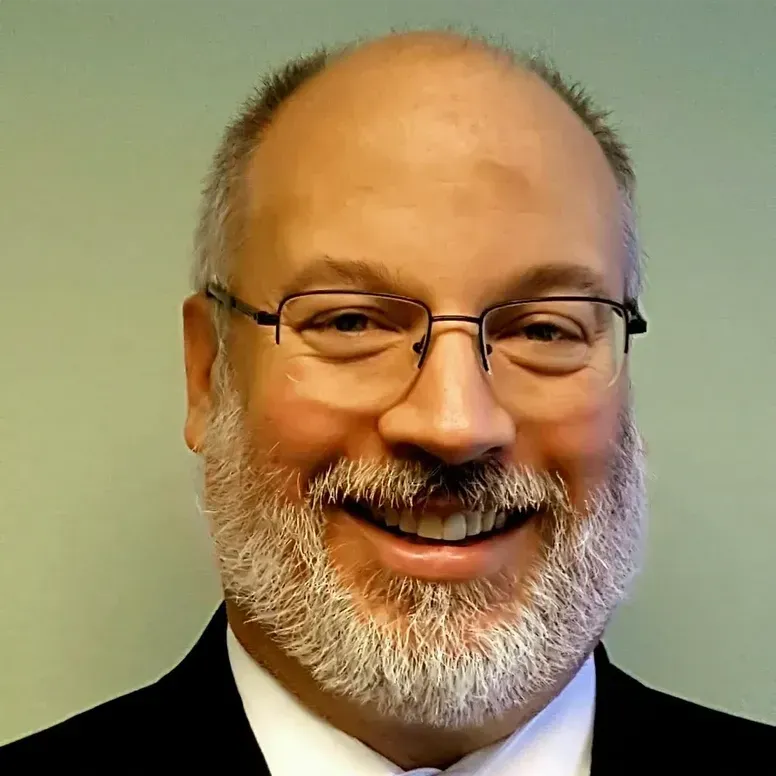 A man with glasses and a beard is smiling for the camera