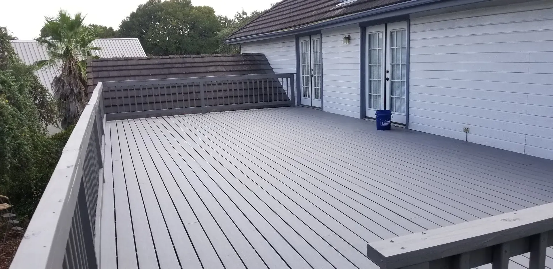 A gray painted wooden deck extends from a white house with dark gray trim.