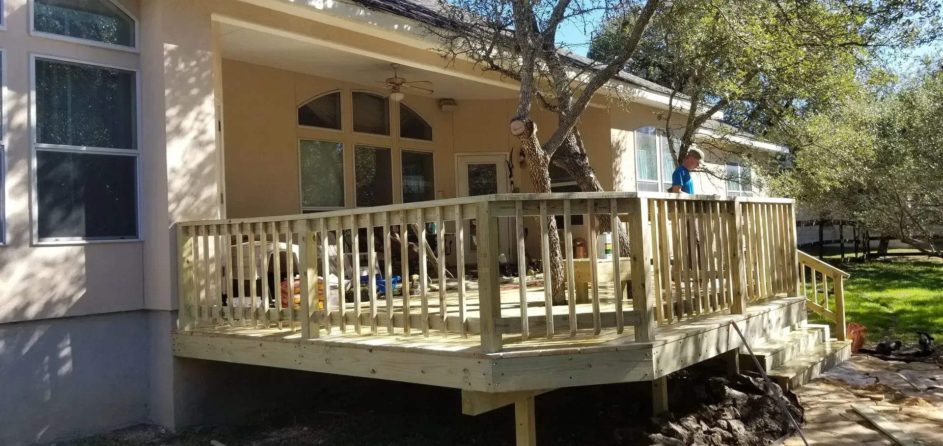 Wooden deck extending from a light-colored house. A child stands near a tree, looking at the yard.