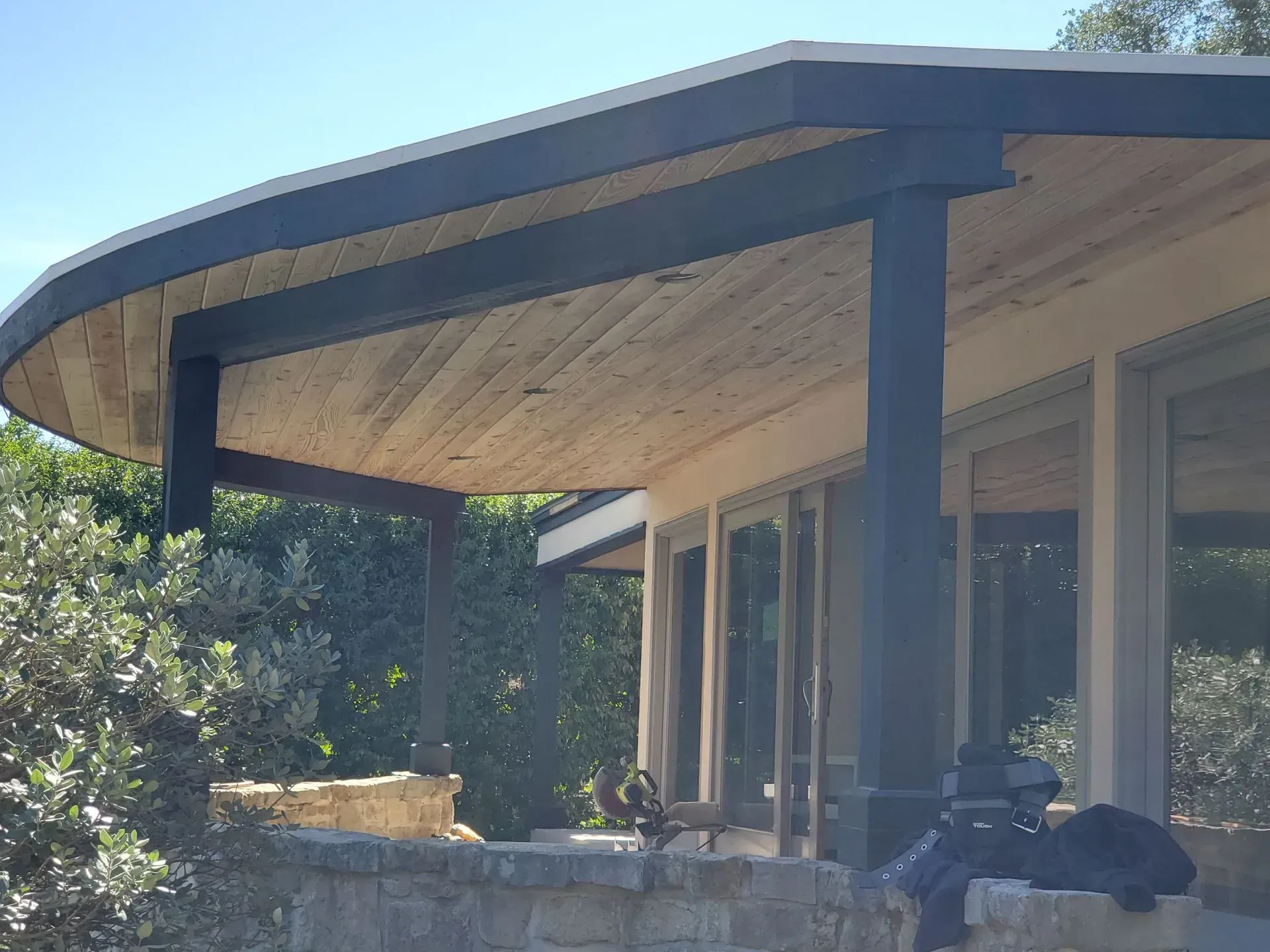 Covered outdoor patio with a curved wooden roof, supported by dark posts.