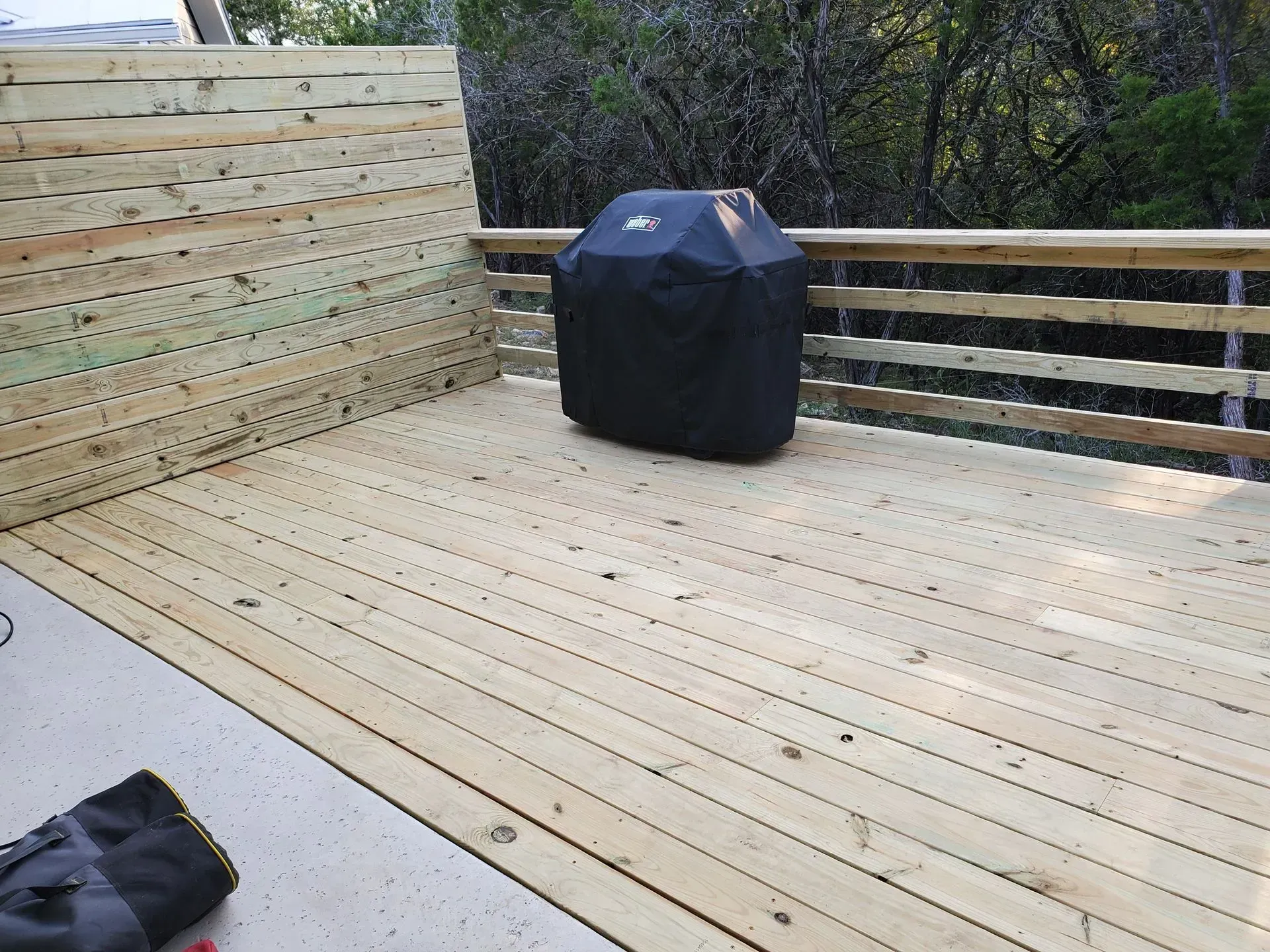 Wooden deck with a covered grill and a horizontal wood privacy screen.