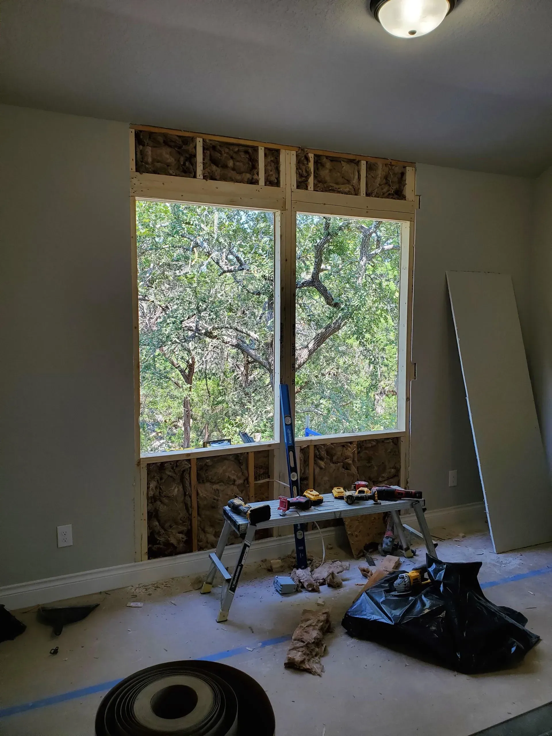 Interior view of a window under construction. Insulation, tools, and materials visible. 