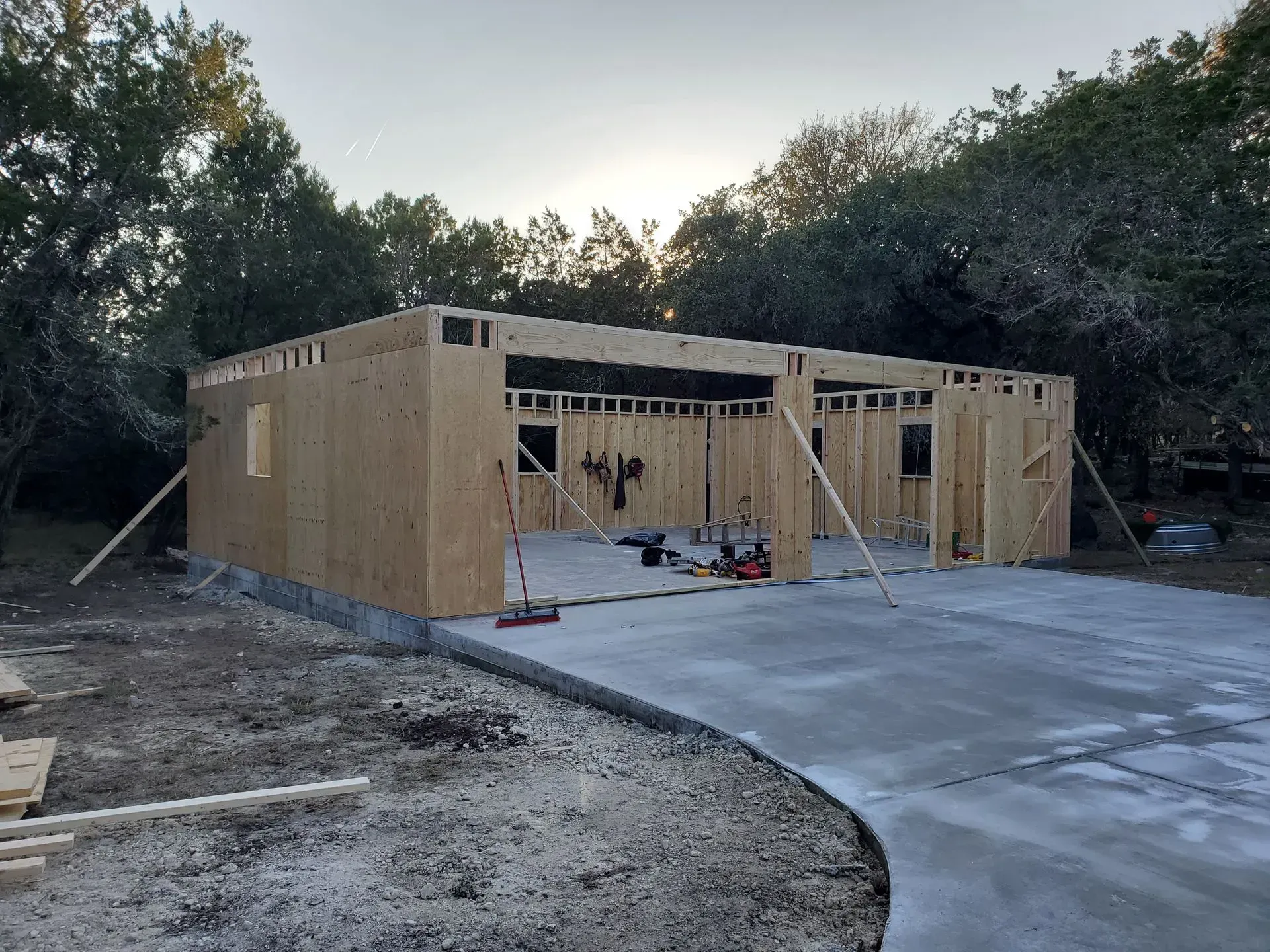 Garage under construction with concrete foundation and driveway. Framing with support beams.