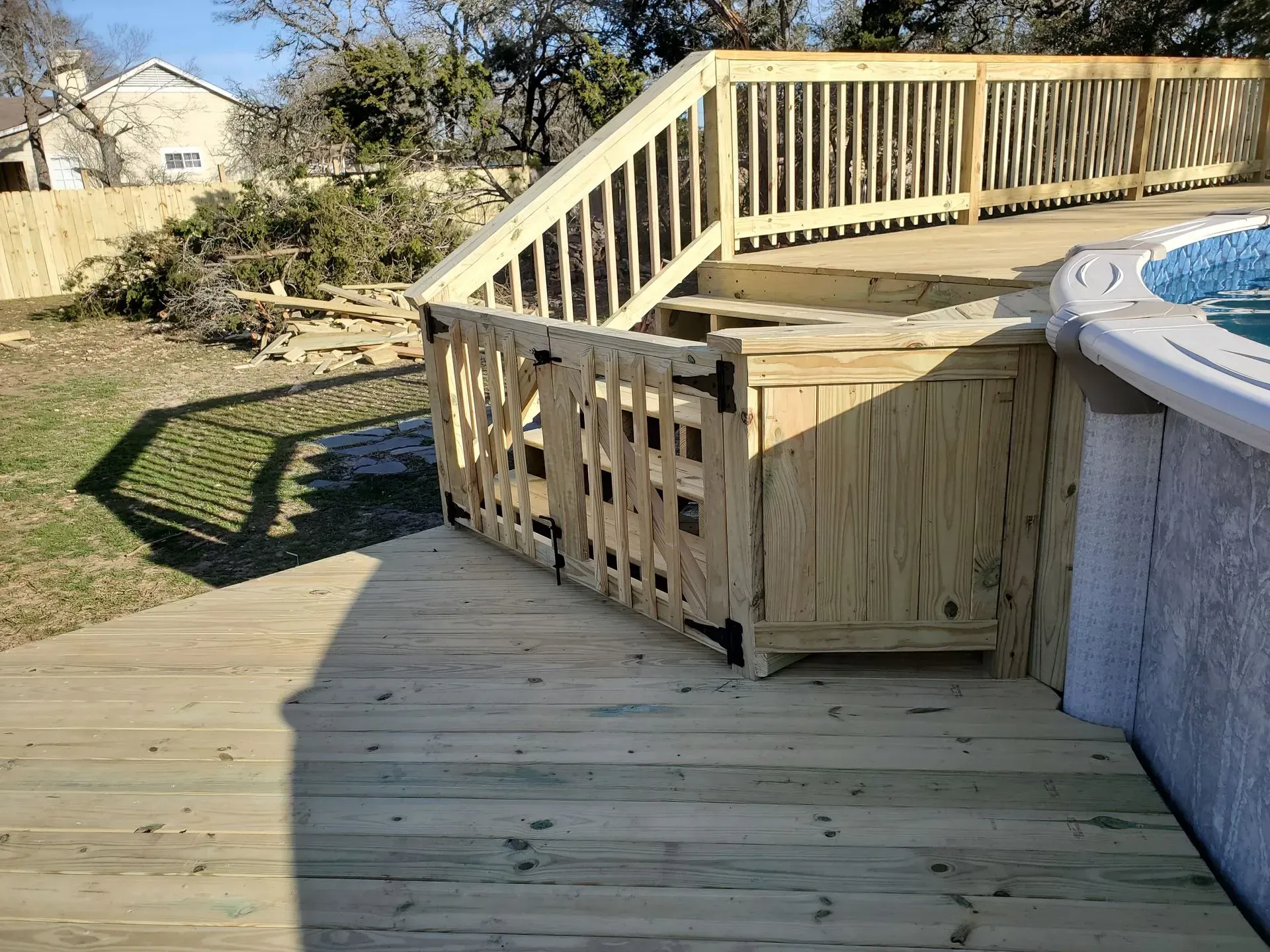 Wooden deck with stairs, railing, and a pool.