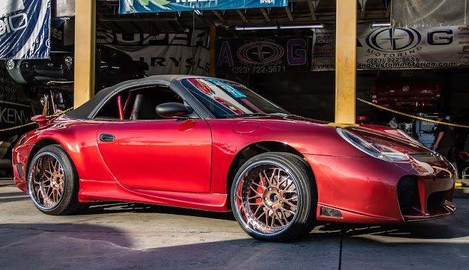 A red sports car is parked in front of a garage.