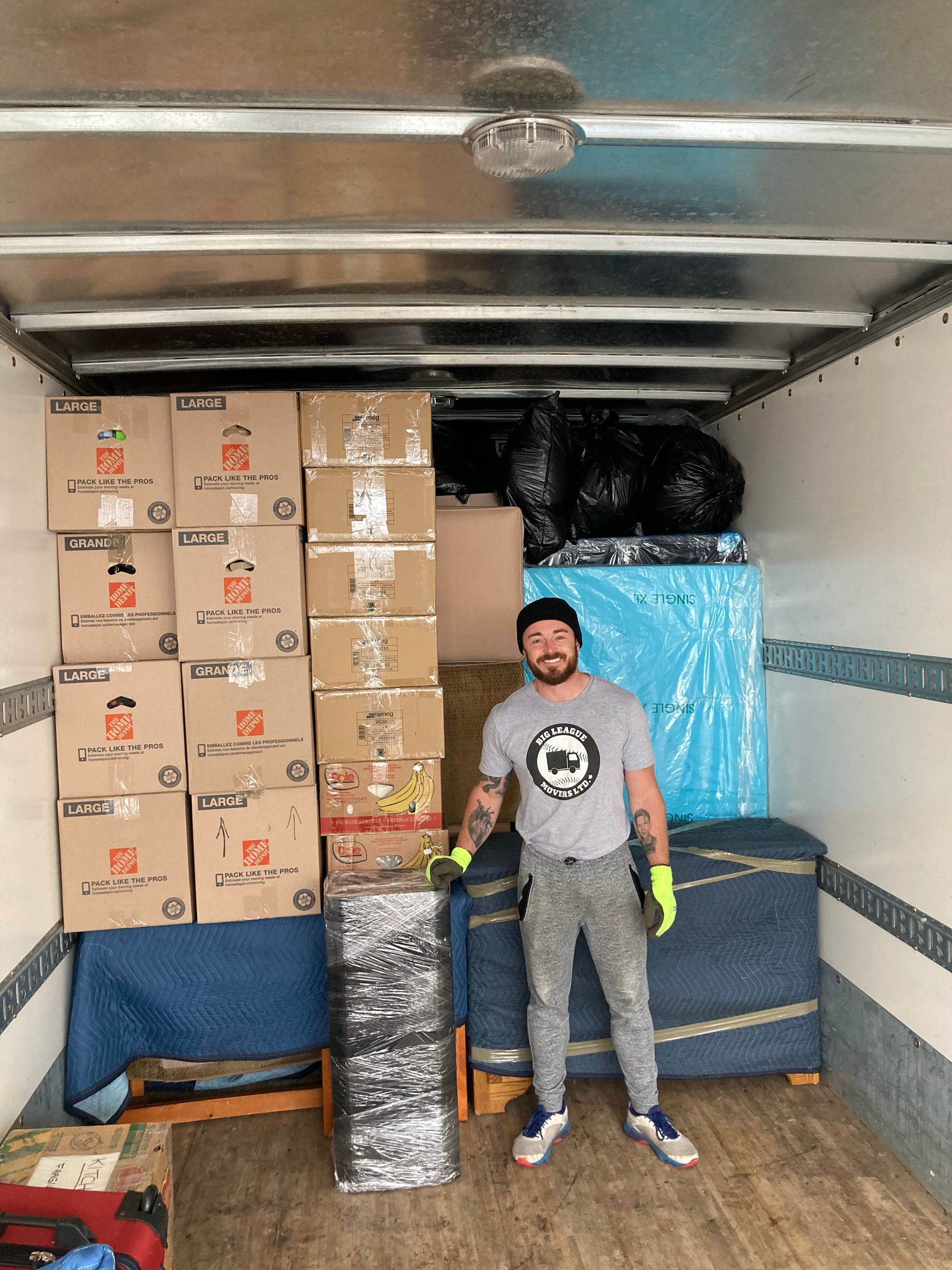 A man is standing in the back of a moving truck filled with boxes.