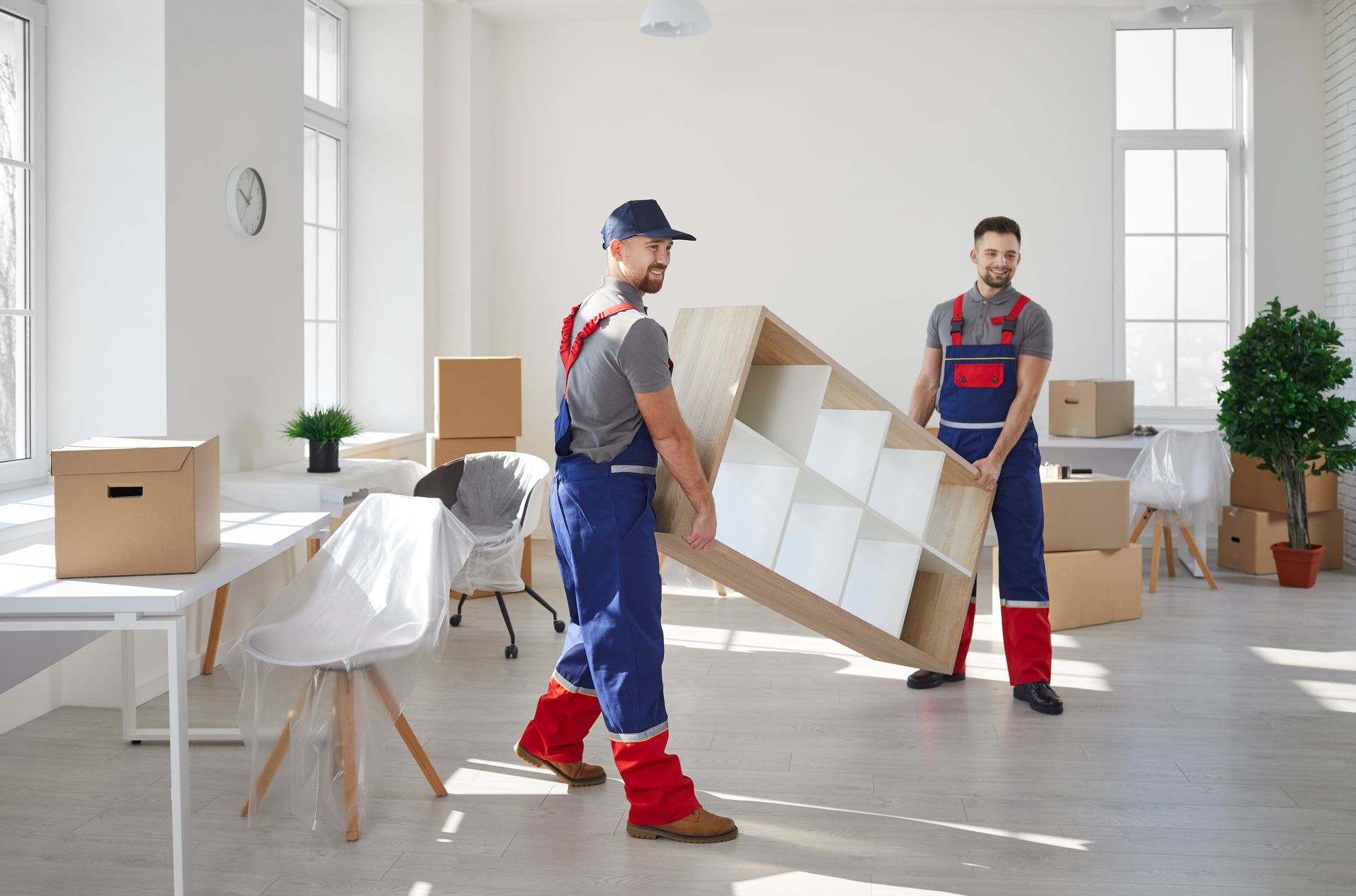 Two men are carrying a shelf in a room.