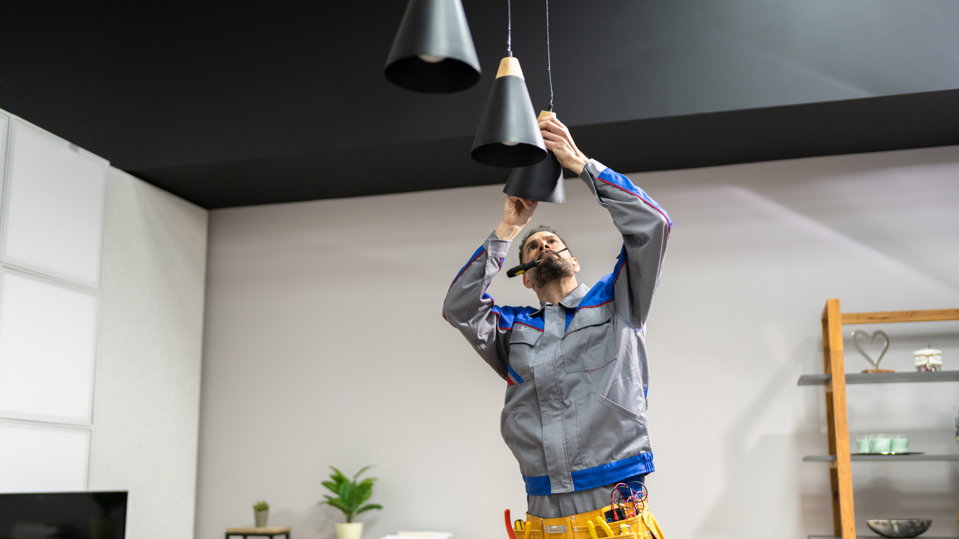 A man is installing a light fixture in a living room.