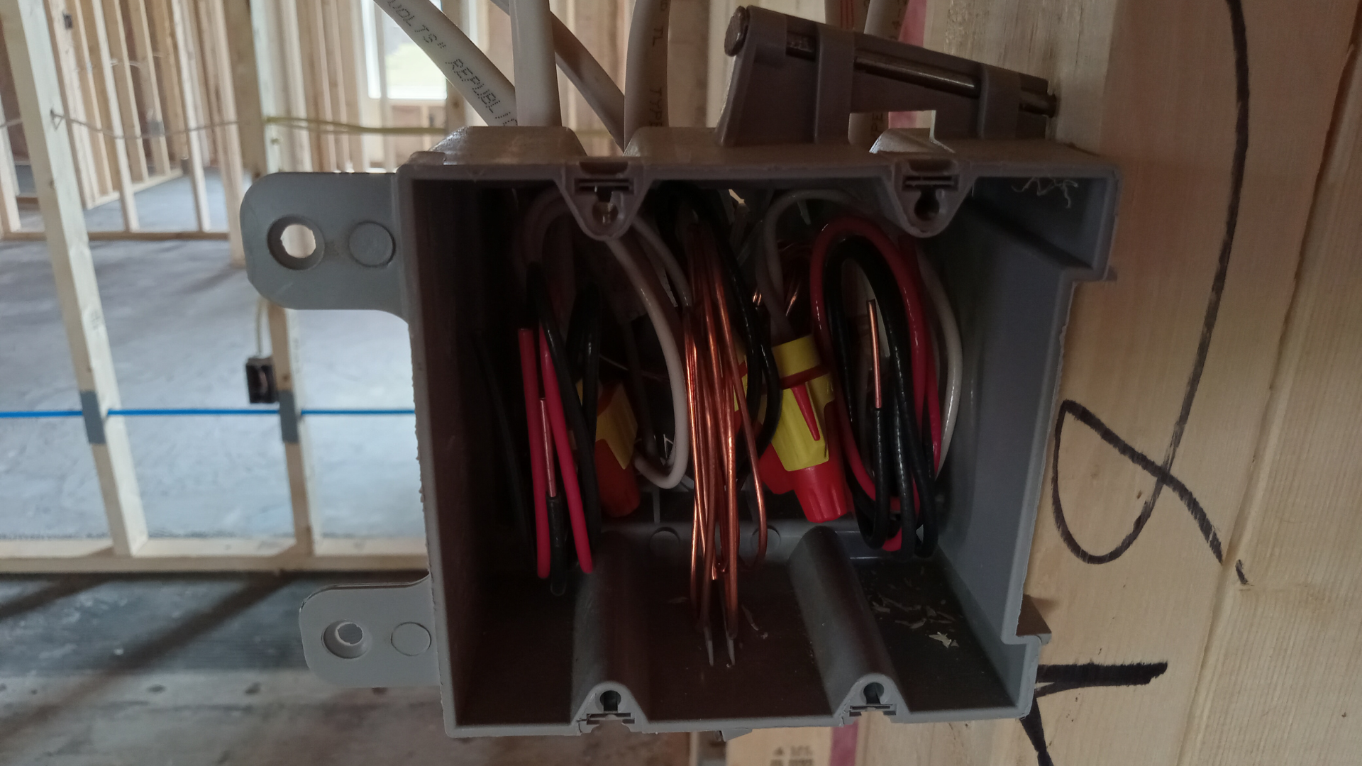 A box with wires in it is hanging on a wall.