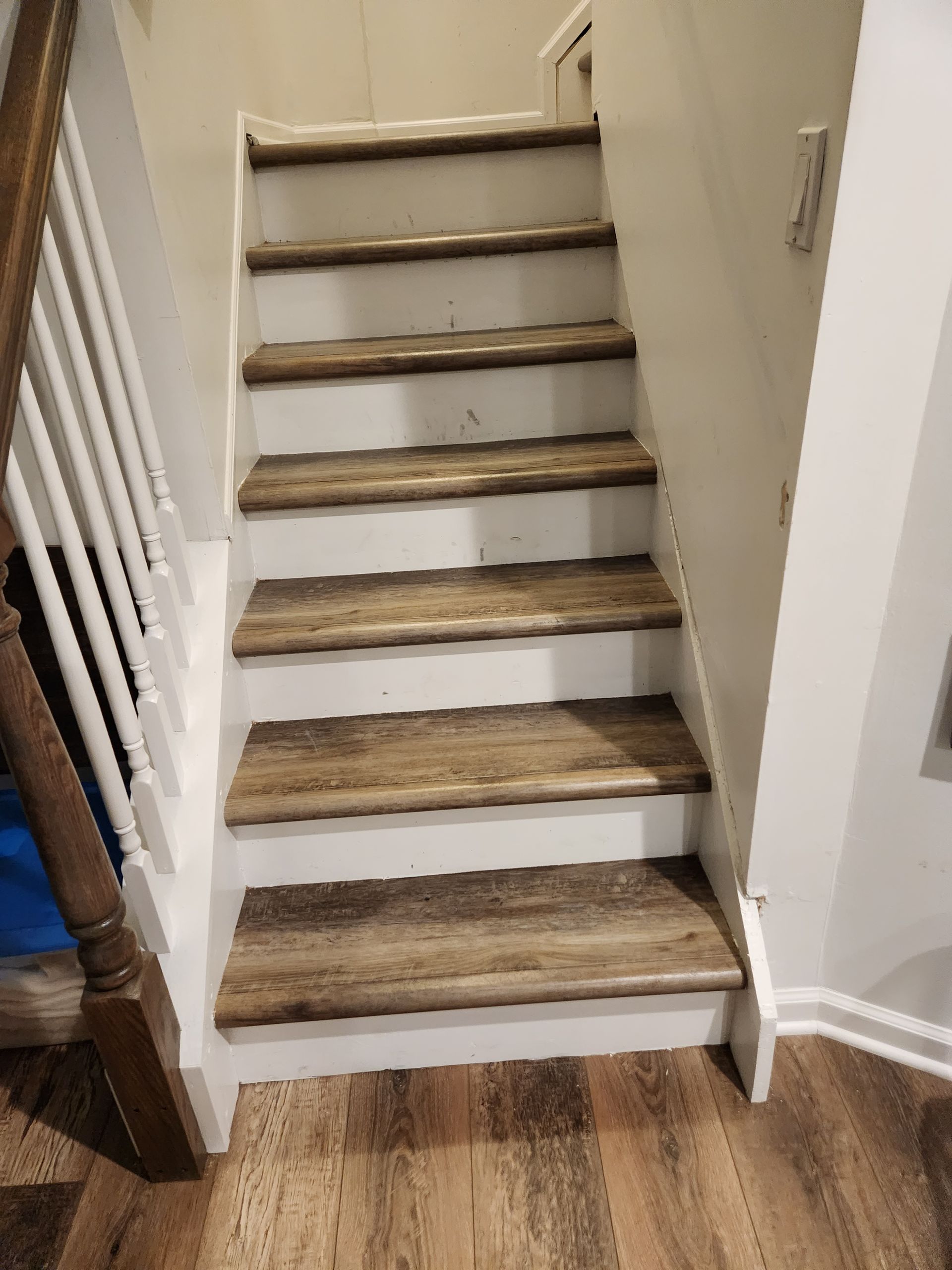 Wooden staircase with white risers and wood-look treads. Handrail on the left.