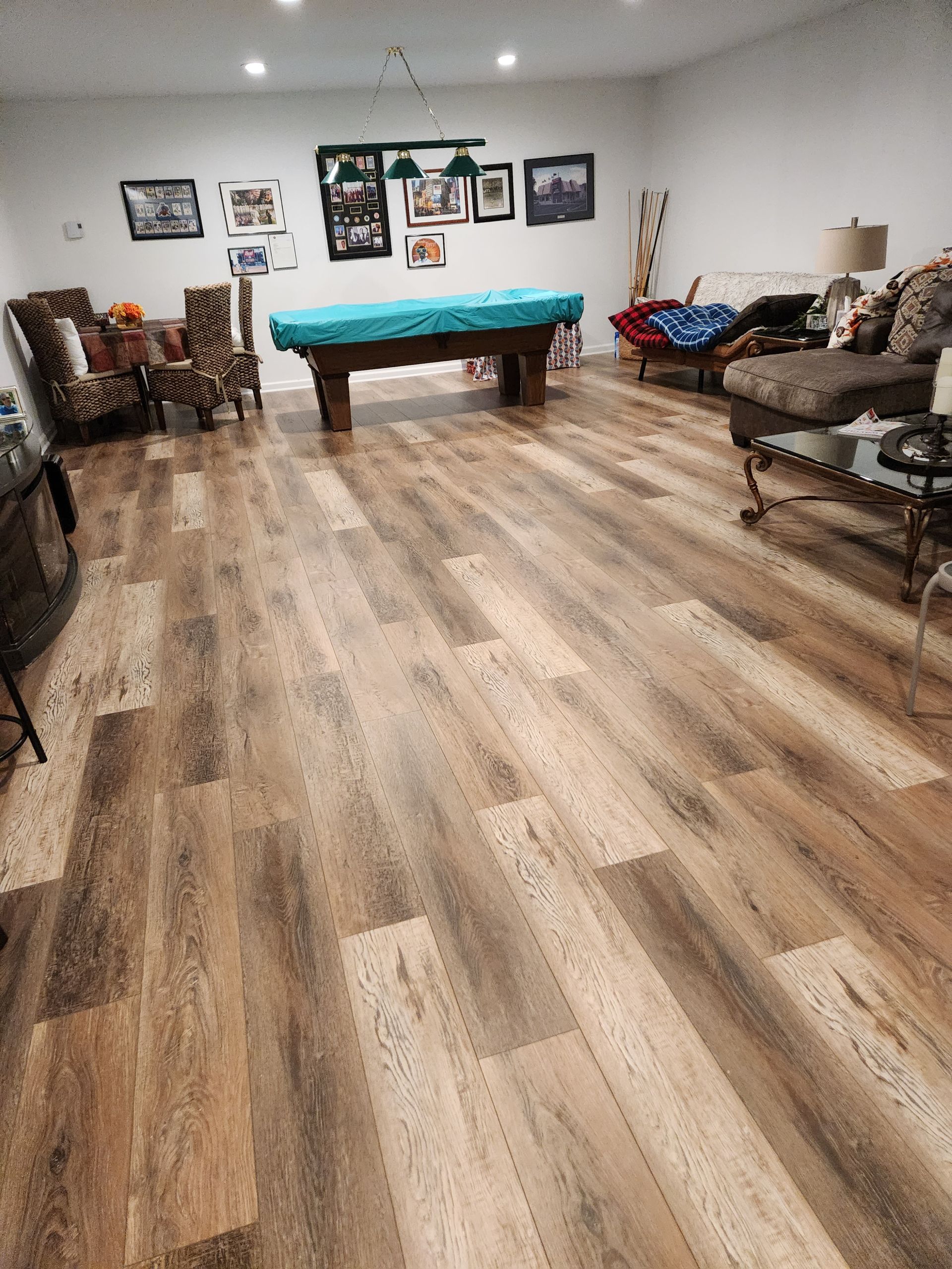 A rec room with a pool table, wooden floor, and seating areas.