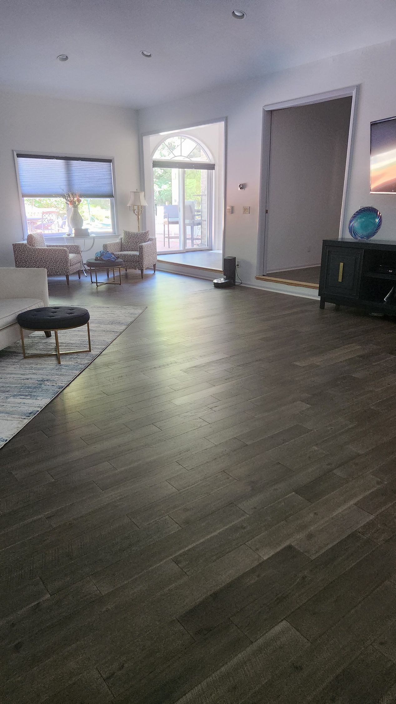 Spacious living room with dark wood flooring, light walls, and a view to an exterior door.