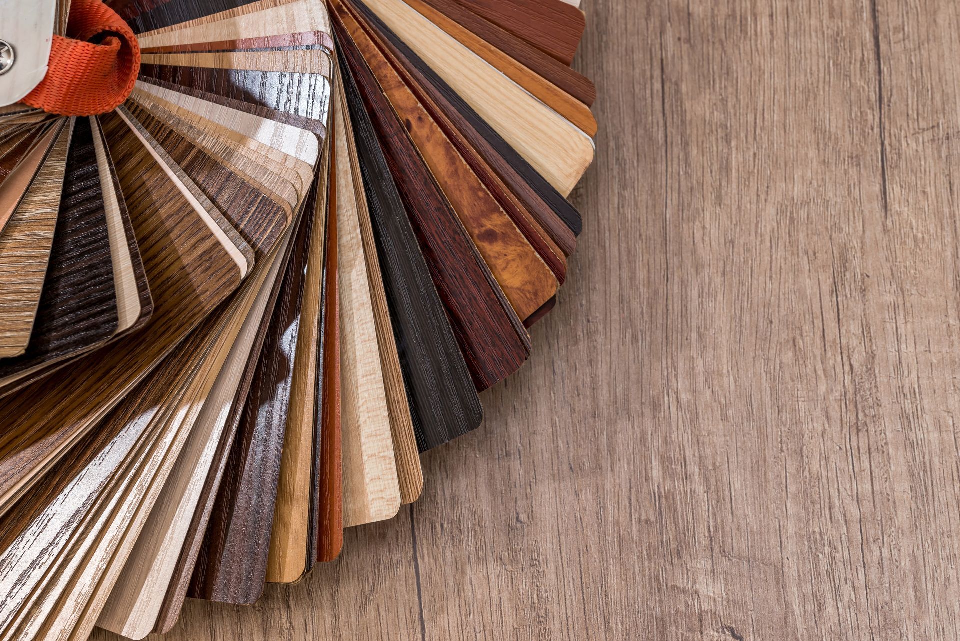 Wood flooring samples fanned out on a wood surface, showcasing various colors and textures.