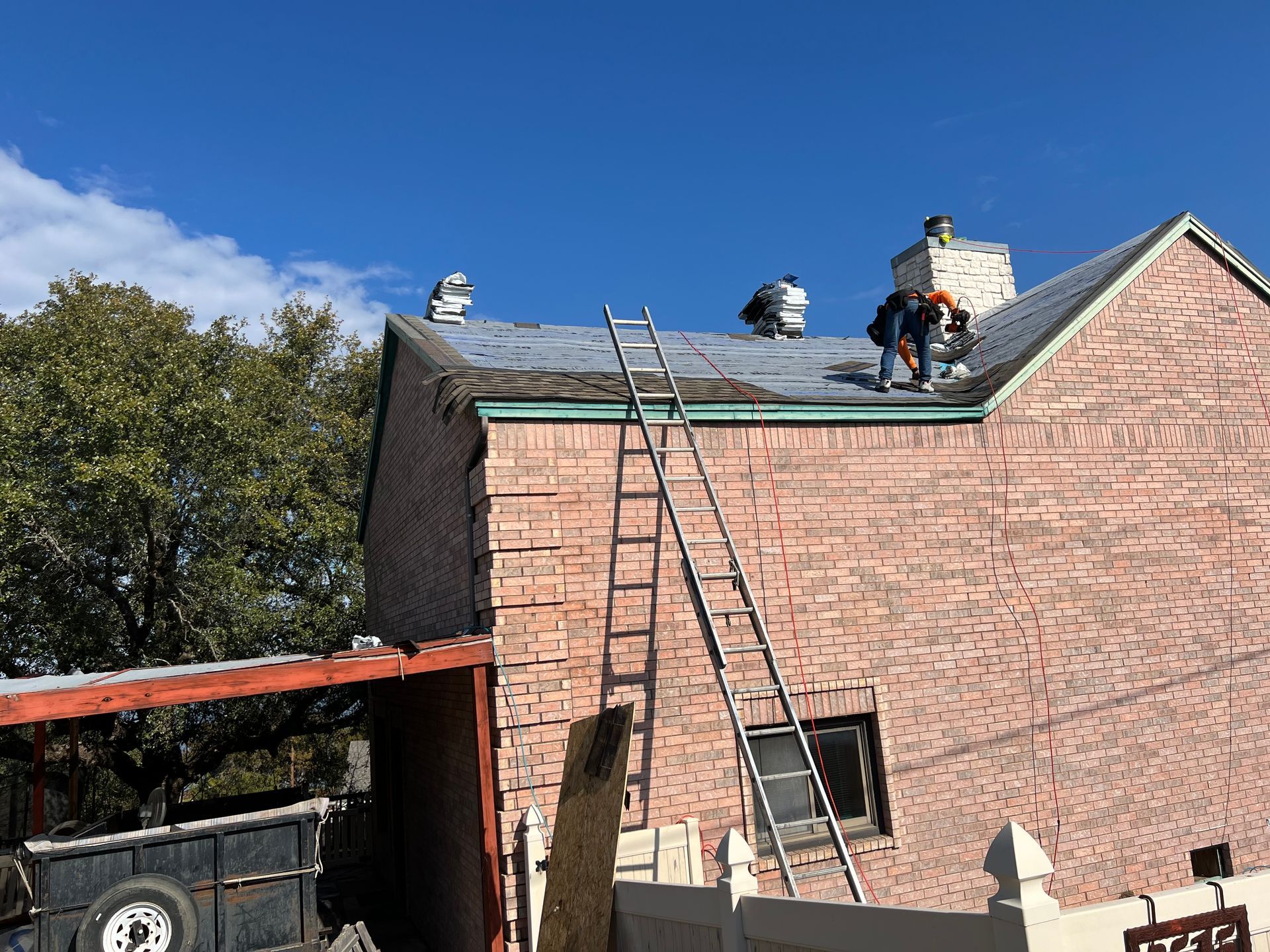 A group of people are working on the roof of a brick building.