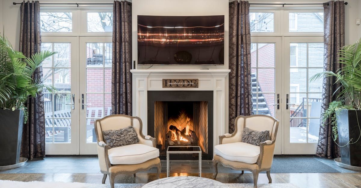 A living room with two chairs , a fireplace and a flat screen tv.