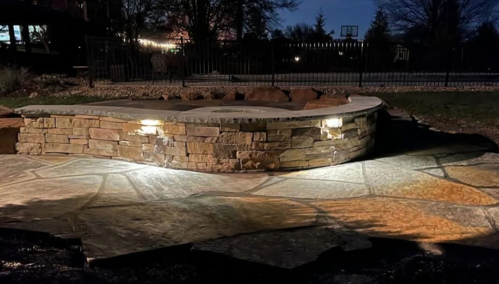 A stone wall with lights on it is lit up at night.