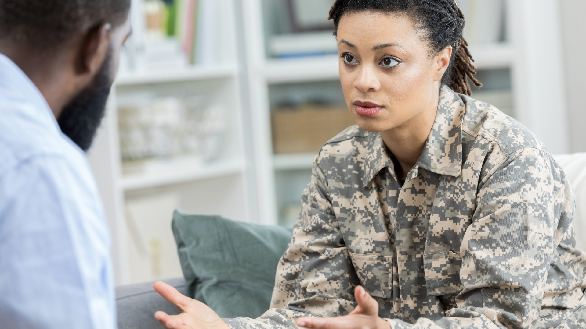 Soldier in camouflage uniform talking to a therapist in a counseling session.