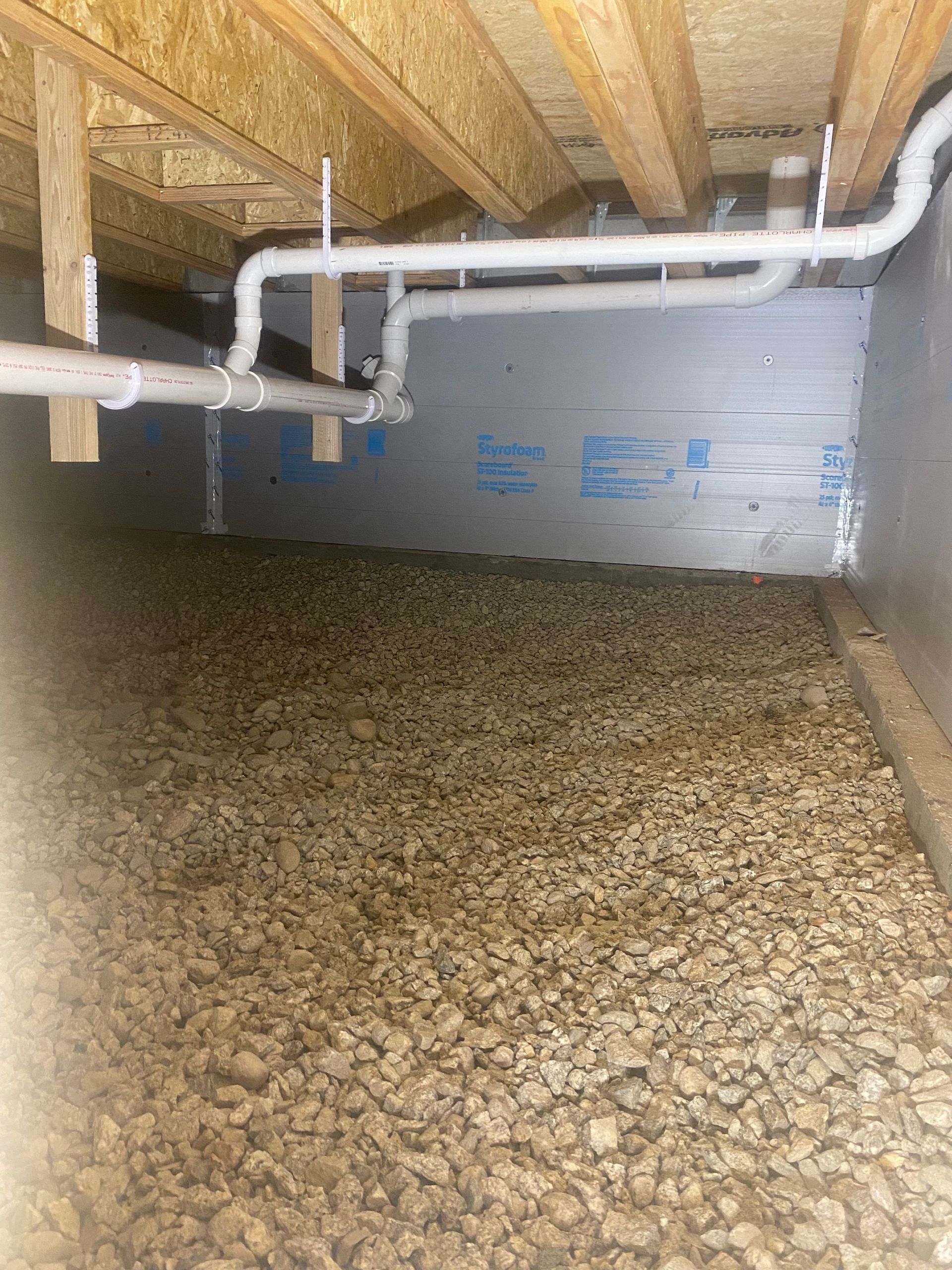 A basement with a lot of rocks and pipes.