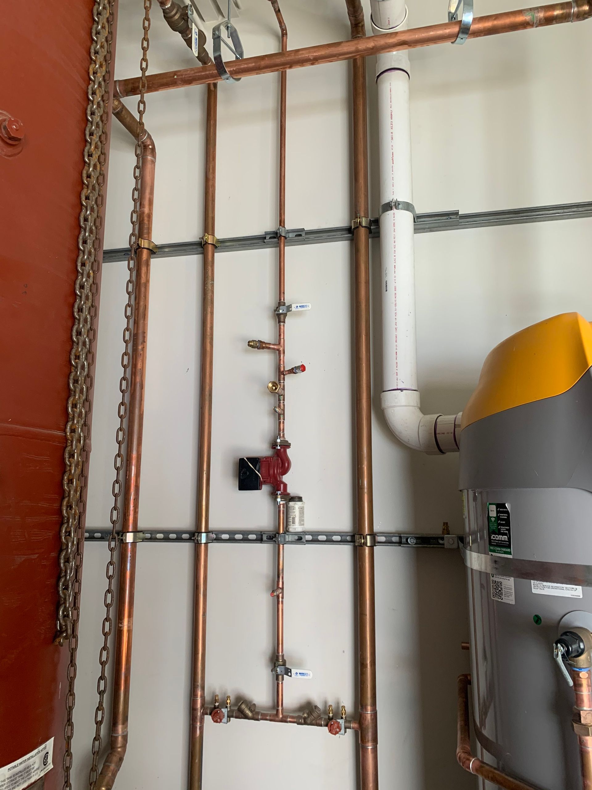 A room with copper pipes and a water heater.