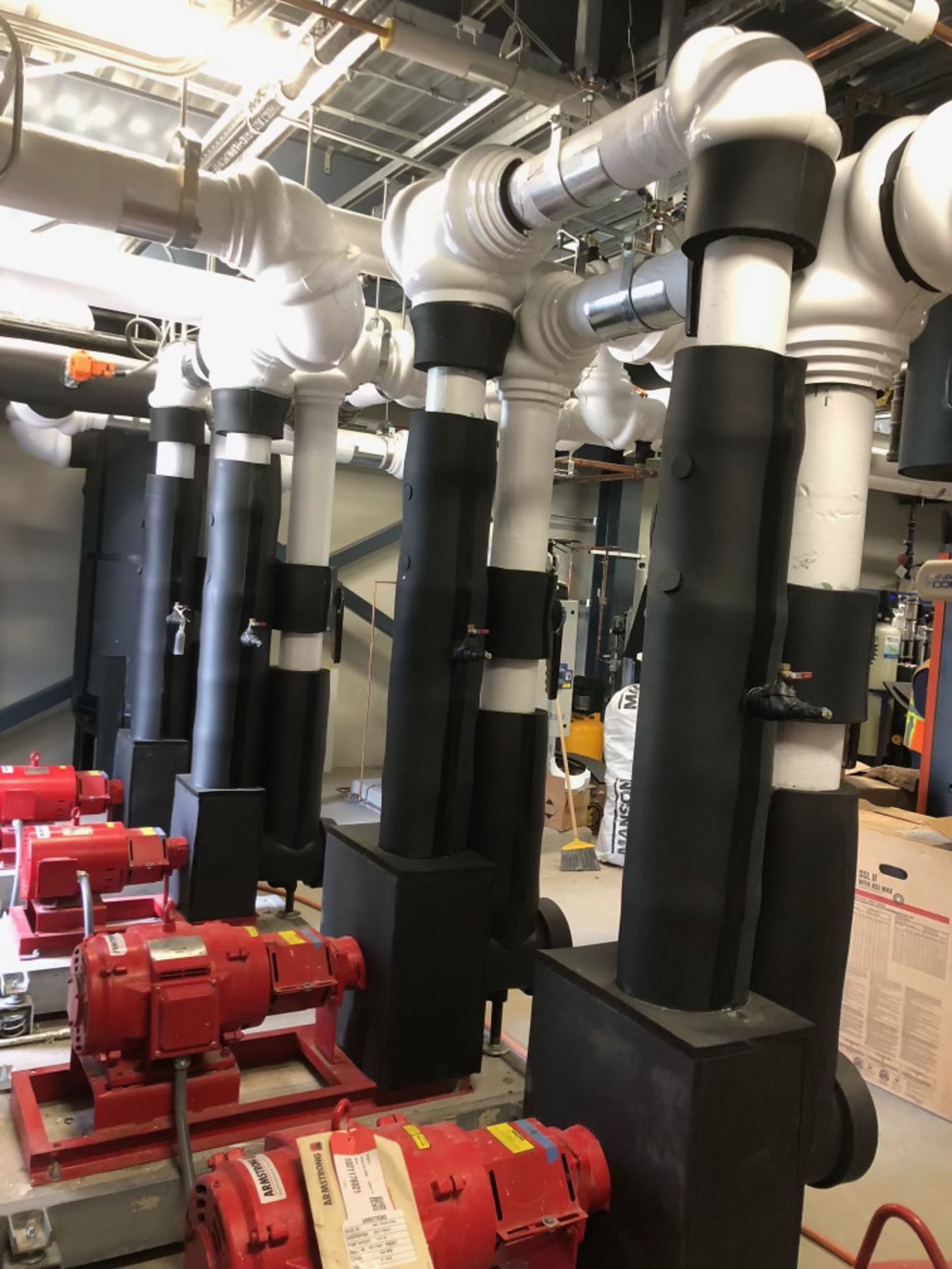 A bunch of pipes and pumps are lined up in a room